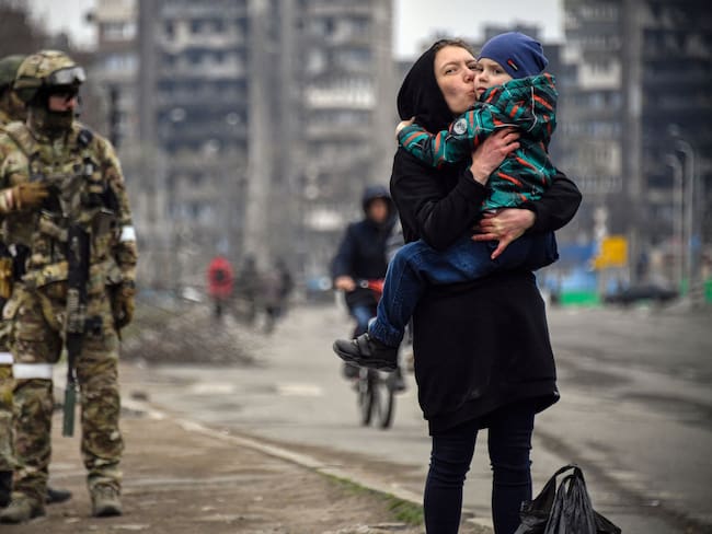 TOPSHOT - A woman holds and kisses a child next to Russian soldiers in a street of Mariupol on April 12, 2022, as Russian troops intensify a campaign to take the strategic port city, part of an anticipated massive onslaught across eastern Ukraine, while Russia&#039;s President makes a defiant case for the war on Russia&#039;s neighbour. - *EDITOR&#039;S NOTE: This picture was taken during a trip organized by the Russian military.* (Photo by Alexander NEMENOV / AFP) (Photo by ALEXANDER NEMENOV/AFP via Getty Images)