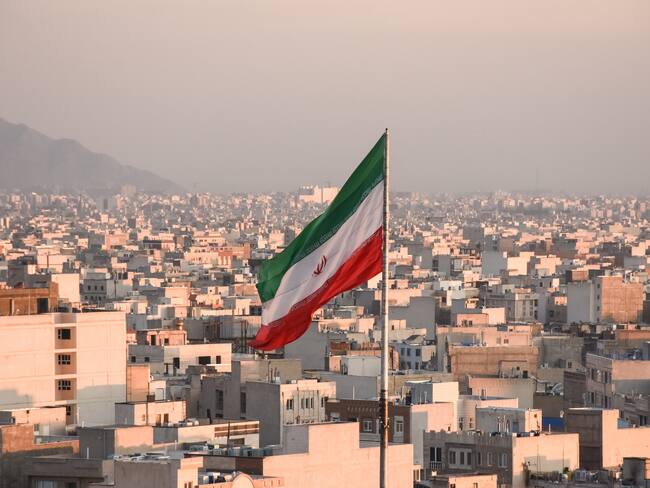 Iranian flag waving with cityscape on background in Tehran, Iran