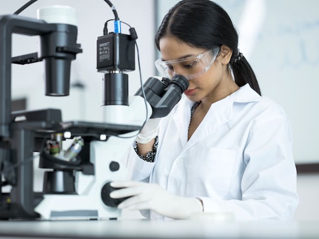 Estudiante de bacteriología mirando a través de un microscópico mientras examina algunas muestras / Foto: GettyImages