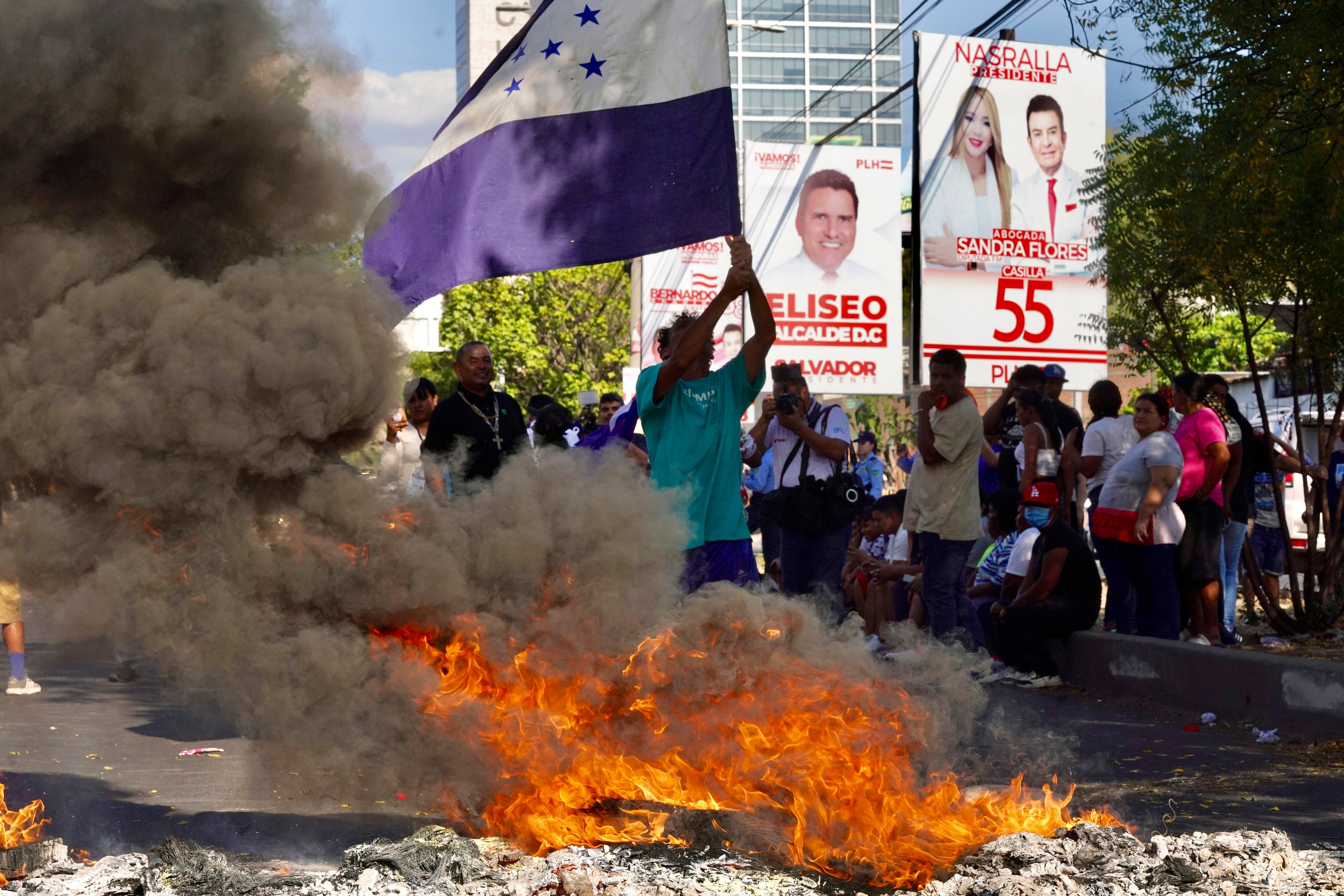 TEGUCIGALPA (HONDURAS), 09/03/2025.- Simpatizantes del Partido Nacional de Honduras ondean banderas y queman llantas en una calle exigiendo que lleguen urnas de votación a su barrio.
