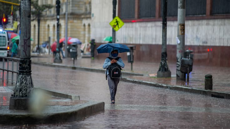 Mujer caminando bajo la lluvia en Bogotá (Foto vía GettyImages)