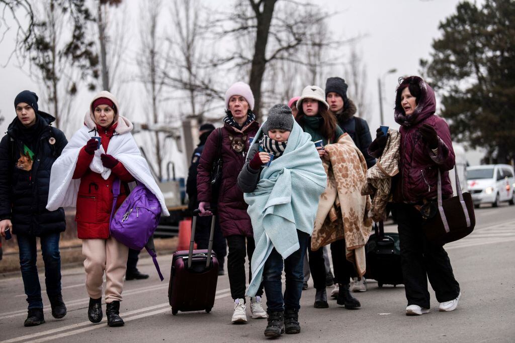 Ukrainian evacuees walk at the Ukrainian-Romanian border in Siret, northern Romania, on March 16, 2022. - More than three million people have fled Ukraine since the start of the invasion, the UN migration agency IOM says. Around half are minors, says the UN children's agency. (Photo by Armend NIMANI / AFP) (Photo by ARMEND NIMANI/AFP via Getty Images)