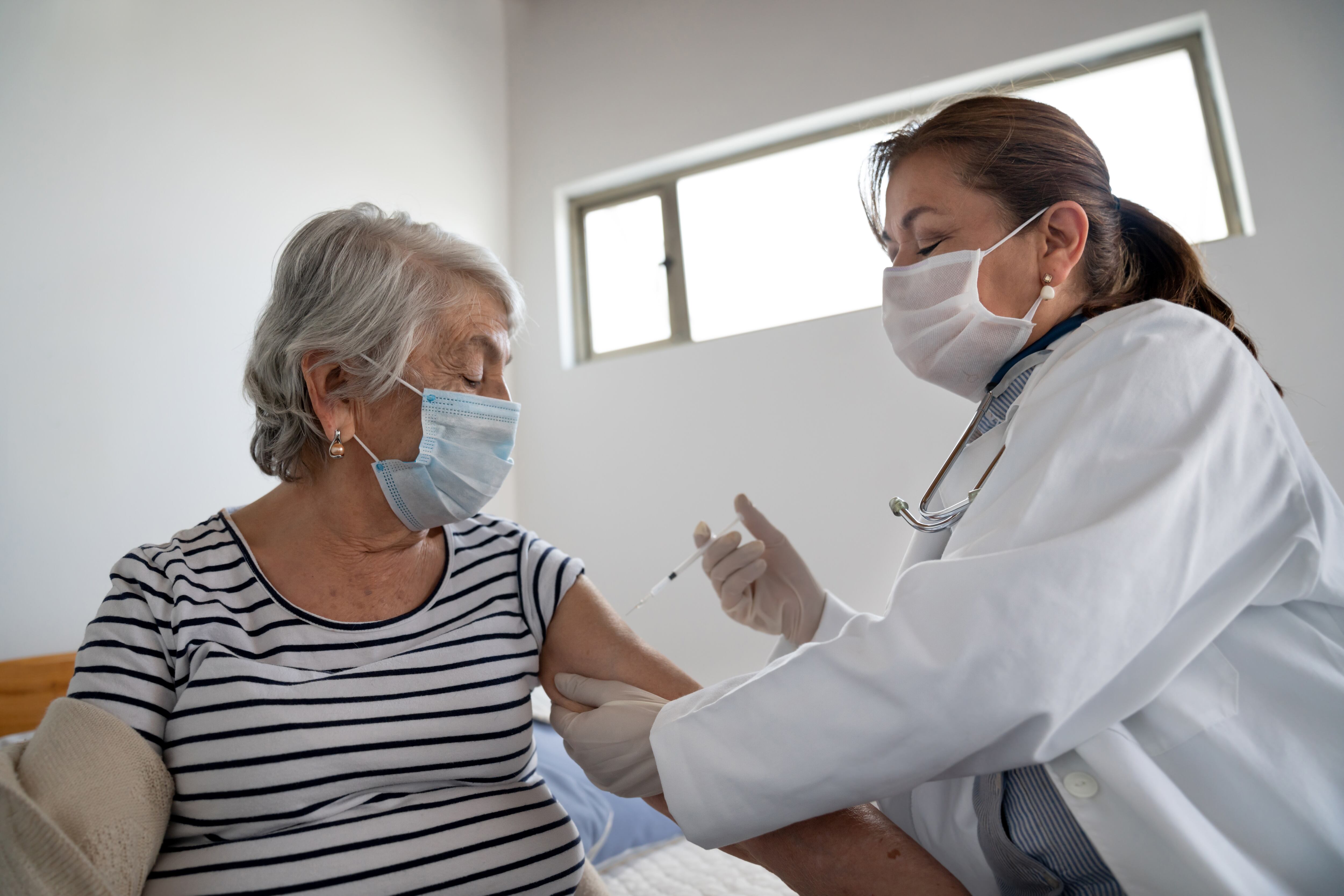 Latin American senior woman getting a COVID-19 vaccine by a doctor at a nursing home illness prevention concepts. Photo: Getty Images