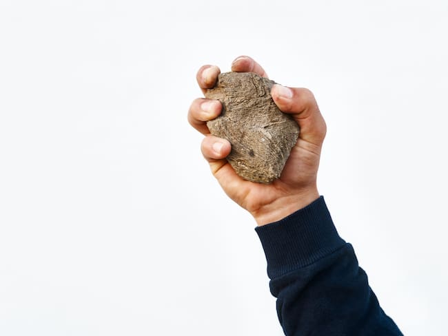 Man&#039;s hand holding a stone to be thrown at a victim of the execution sentence by stoning.