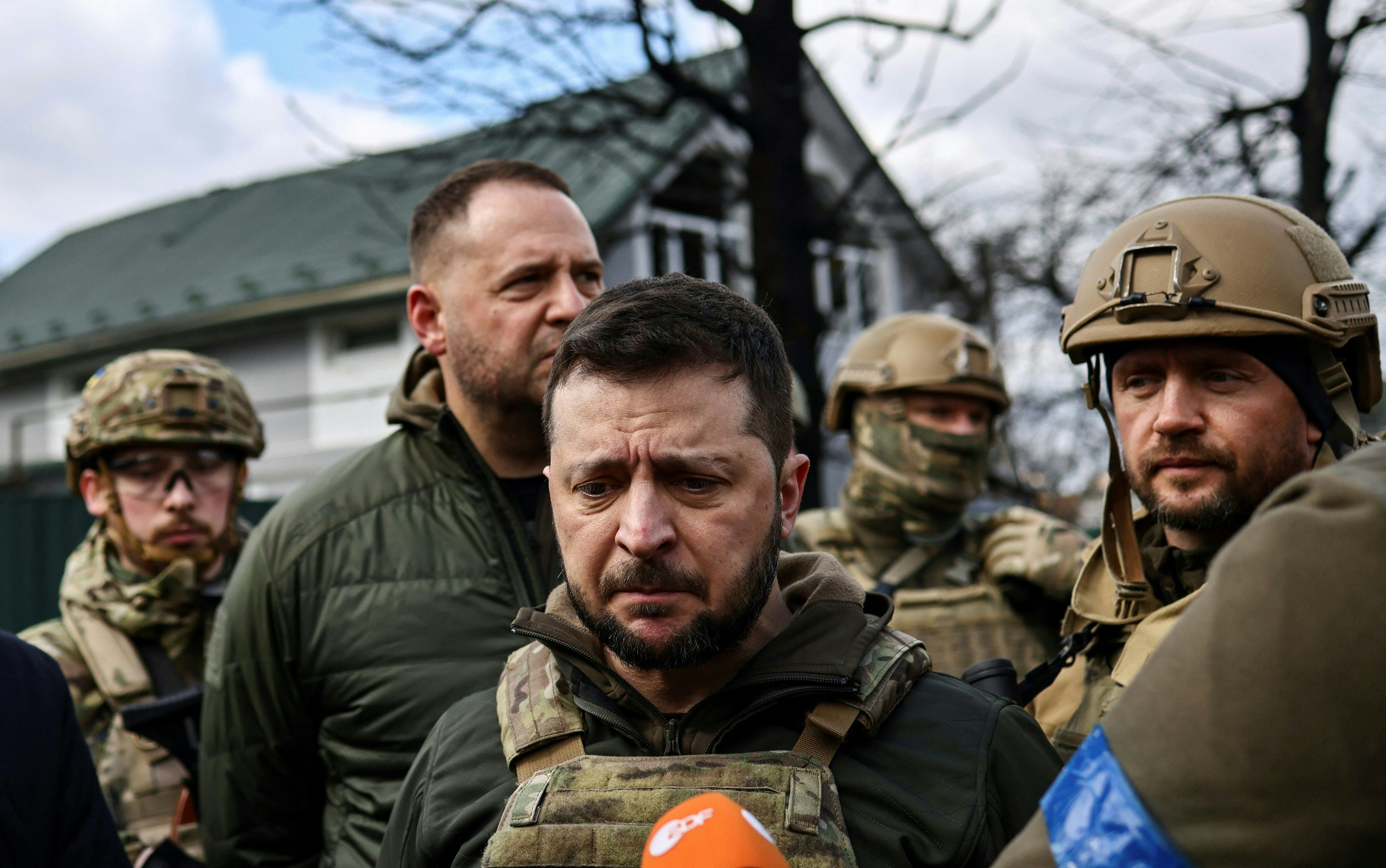 Ukainian President Volodymyr Zelensky (C) speaks to the press in the town of Bucha, northwest of the Ukrainian capital Kyiv, on April 4, 2022. - Ukraine's President Volodymyr Zelensky said on April 3, 2022 the Russian leadership was responsible for civilian killings in Bucha, outside Kyiv, where bodies were found lying in the street after the town was retaken by the Ukrainian army. (Photo by RONALDO SCHEMIDT / AFP) (Photo by RONALDO SCHEMIDT/AFP via Getty Images)