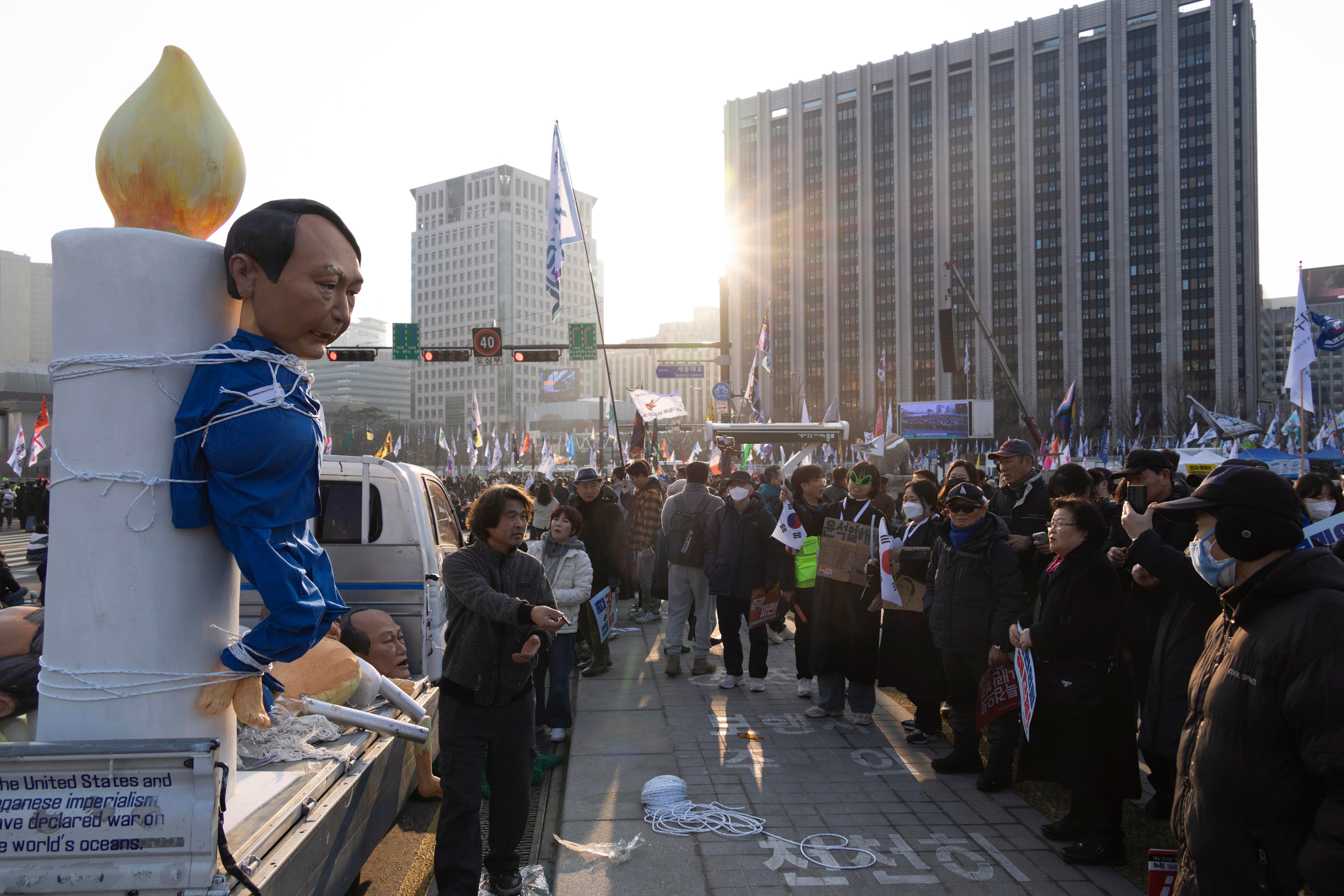 Seúl (Corea del Sur), 01/02/2025.- Manifestantes observan una efigie que representa al presidente destituido de Corea del Sur, Yoon Suk Yeol (izq.), durante una concentración para exigir la dimisión del mandatario.