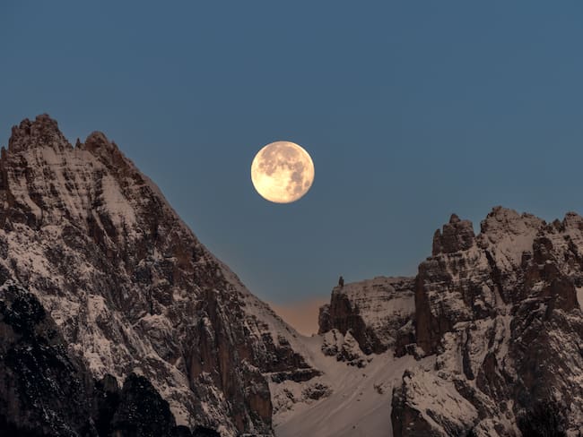 Vista panorámica de la Luna llena en medio de unas montañas nevadas (Foto vía GettyImages)