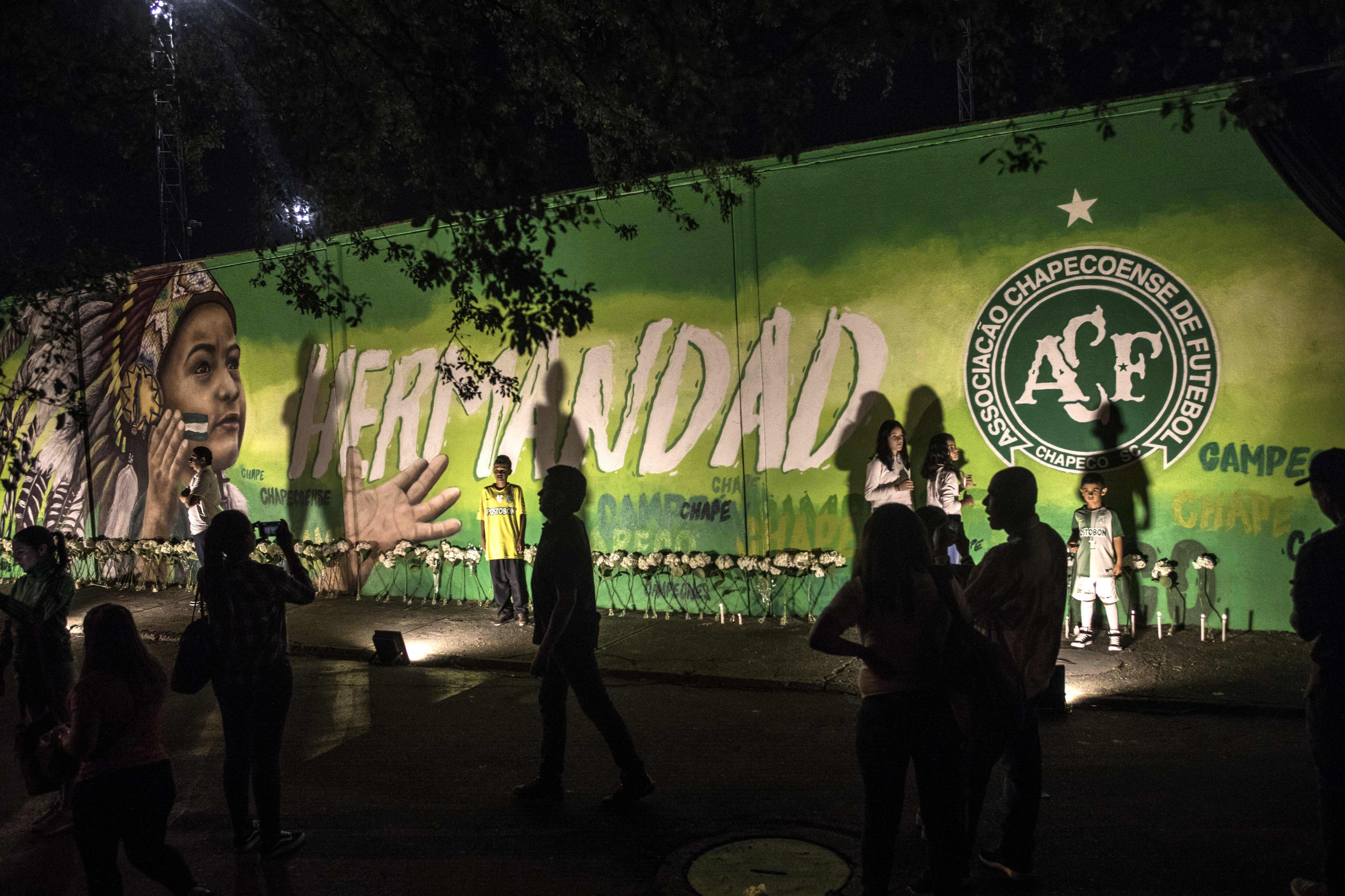 Locals pose for photos after the presentation of a mural in honour of the victims and survivors of Lamia flight 2933 on the first anniversary of the plane crash in Colombia that wiped out the Chapecoense Brazilian football club, in Medellin next to the Atanasio Girardot stadium, Colombia, on November 29, 2017. The plane was flying Chapecoense to Medellin to take on Atletico Nacional in the Copa Sudamericana finals - the biggest and most unexpected game in the Brazilian team's history. When the plane ran out of fuel and went down in inhospitable mountains near its destination, 71 of the 77 aboard died, including 19 players. / AFP PHOTO / JOAQUIN SARMIENTO        (Photo credit should read JOAQUIN SARMIENTO/AFP via Getty Images)