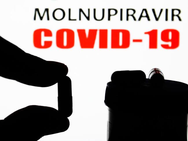 Medicine pill is seen with words 'Molnupiravir' and 'COVID-19' displayed on a screen in the background in this illustration photo taken in Poland on November 5, 2021. (Photo by Jakub Porzycki/NurPhoto via Getty Images)