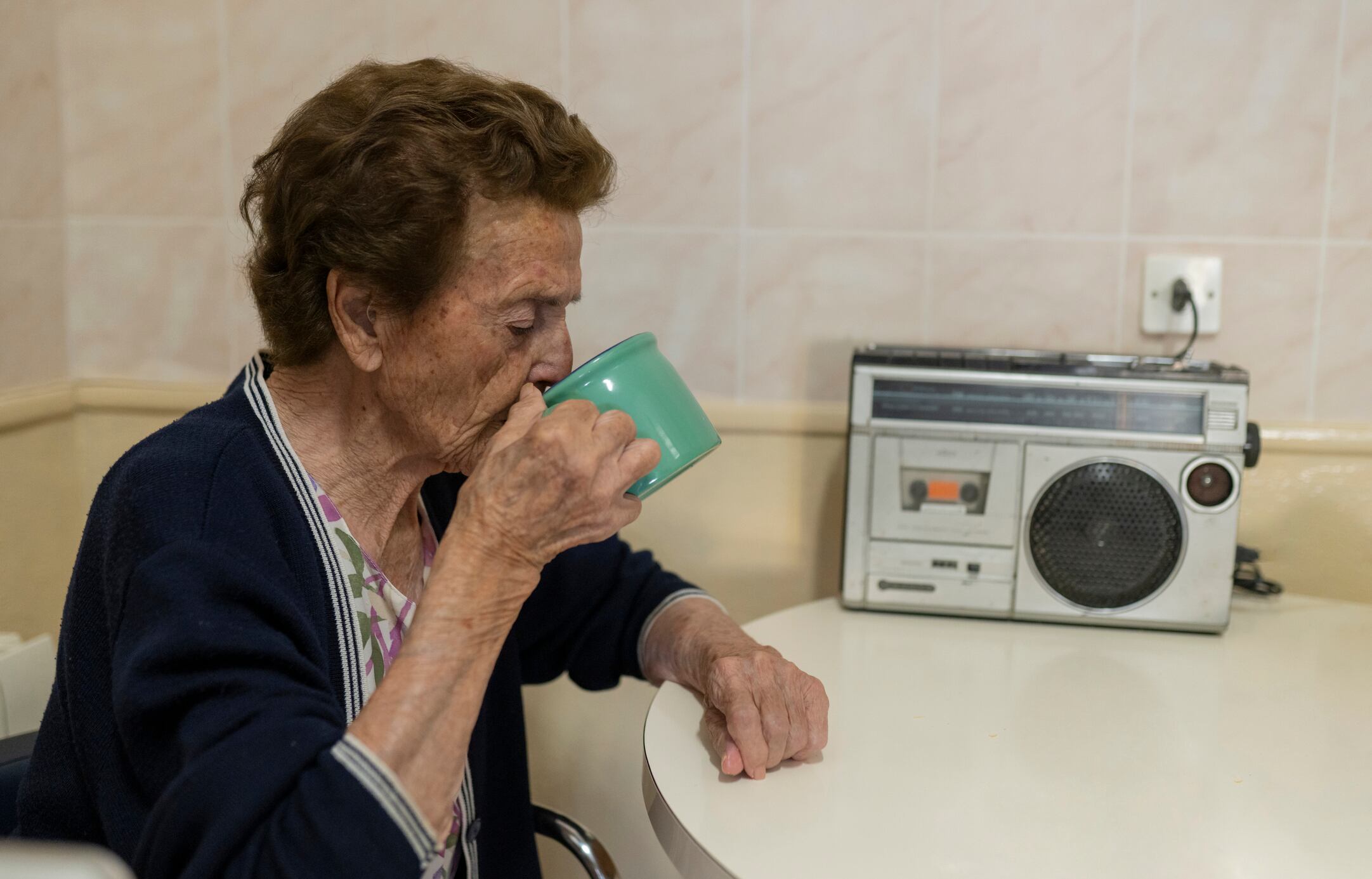 Mujer mayor tomando una bebida caliente mientras escucha radio (Getty Images)