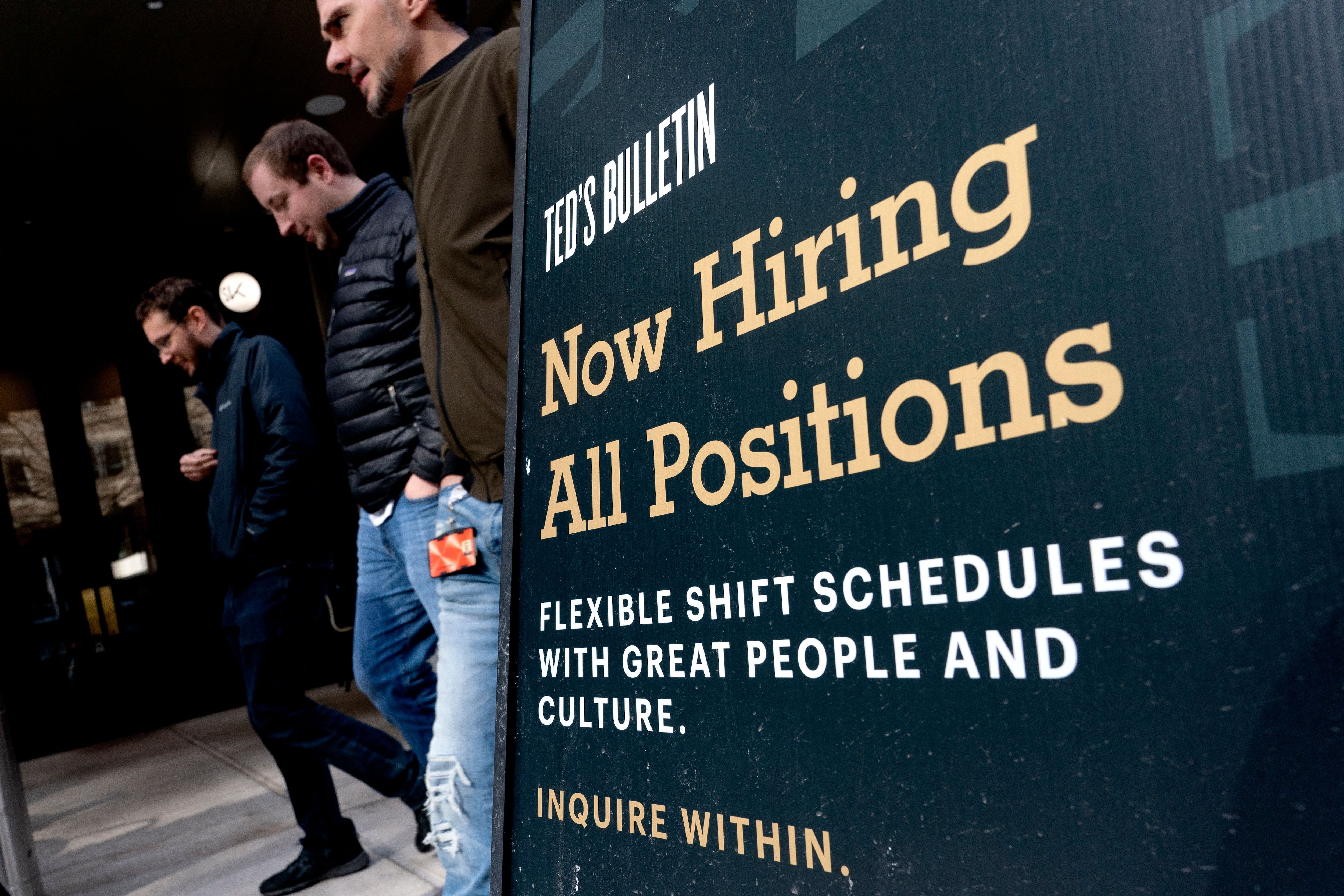 Los peatones pasan frente a un cartel de Now Hiring en Arlington, Virginia, el 16 de marzo de 2022. (Photo by Stefani Reynolds / AFP) (Photo by STEFANI REYNOLDS/AFP via Getty Images)