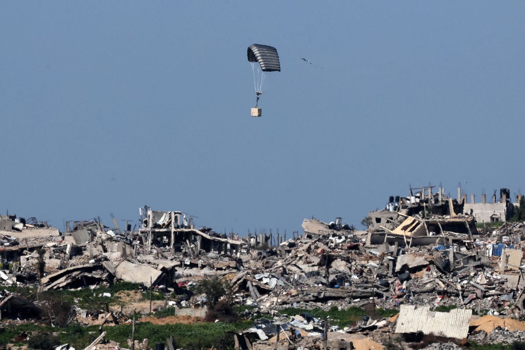 Un paracaídas del ejército israelí deja caer una caja sobre edificios destruidos en la Franja de Gaza, en medio de los combates entre Israel y Hamás. (Photo by JACK GUEZ / AFP) (Photo by JACK GUEZ/AFP via Getty Images)