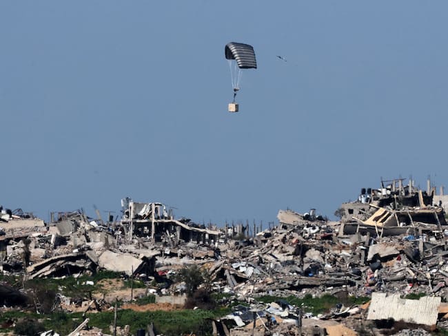 Un paracaídas del ejército israelí deja caer una caja sobre edificios destruidos en la Franja de Gaza, en medio de los combates entre Israel y Hamás. (Photo by JACK GUEZ / AFP) (Photo by JACK GUEZ/AFP via Getty Images)