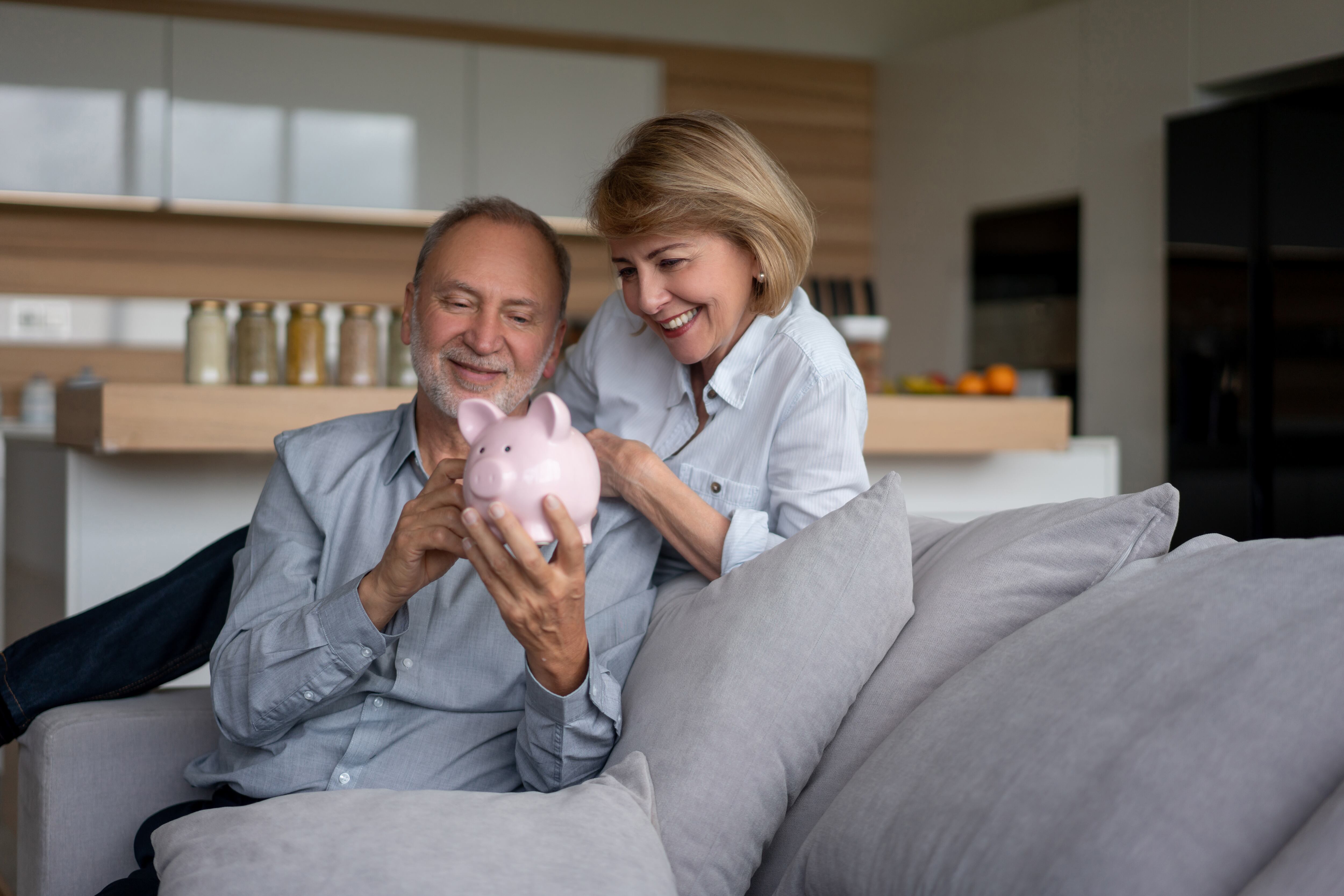 Imagen de una pareja mayor en casa sosteniendo sus ahorros en una alcancía. Getty Images