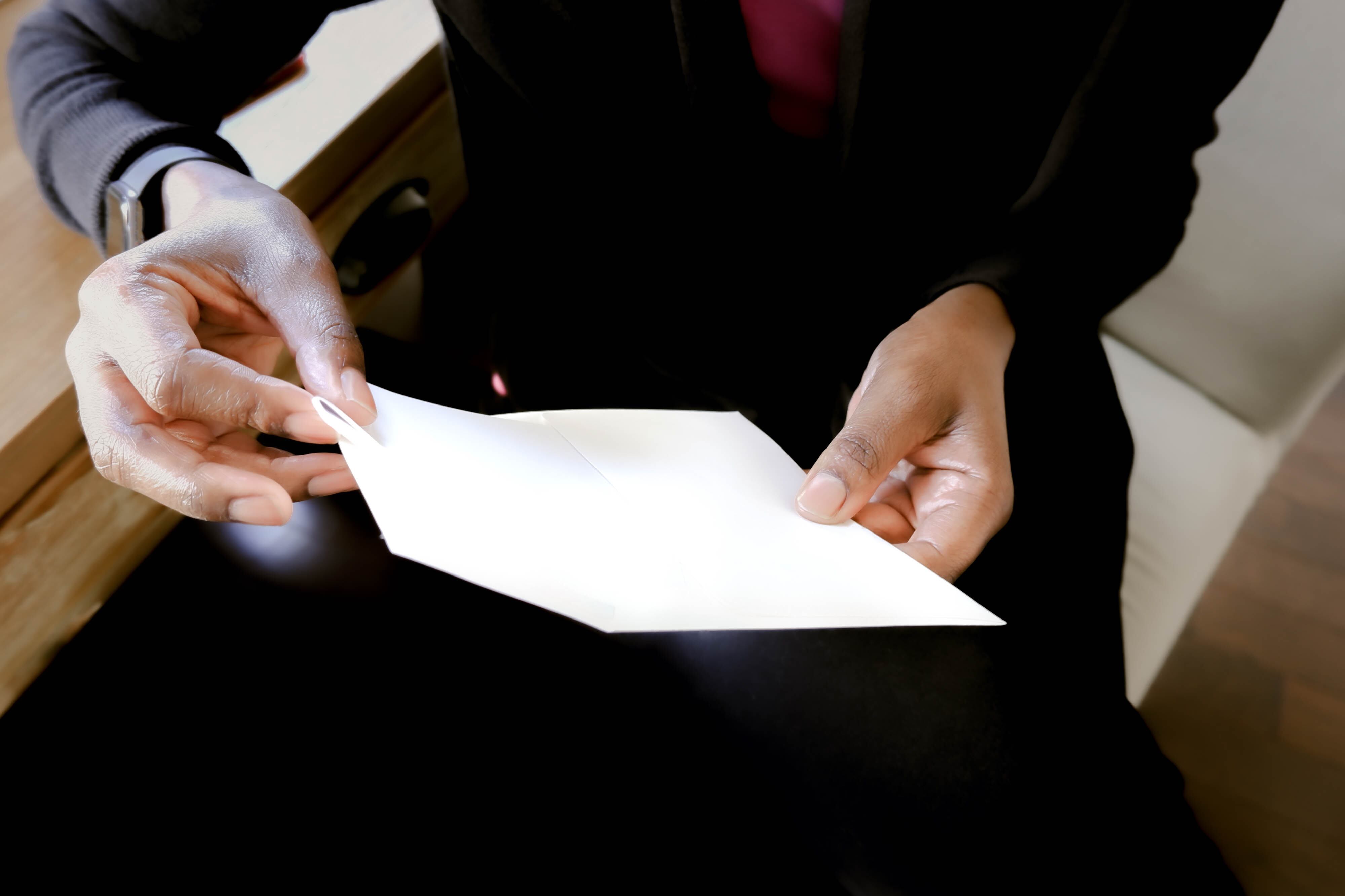 Close-up of unrecognizable black woman inserting letter into envelope