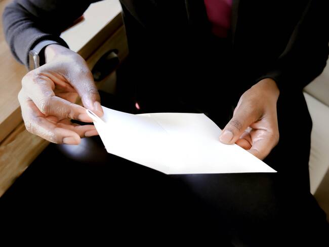 Close-up of unrecognizable black woman inserting letter into envelope