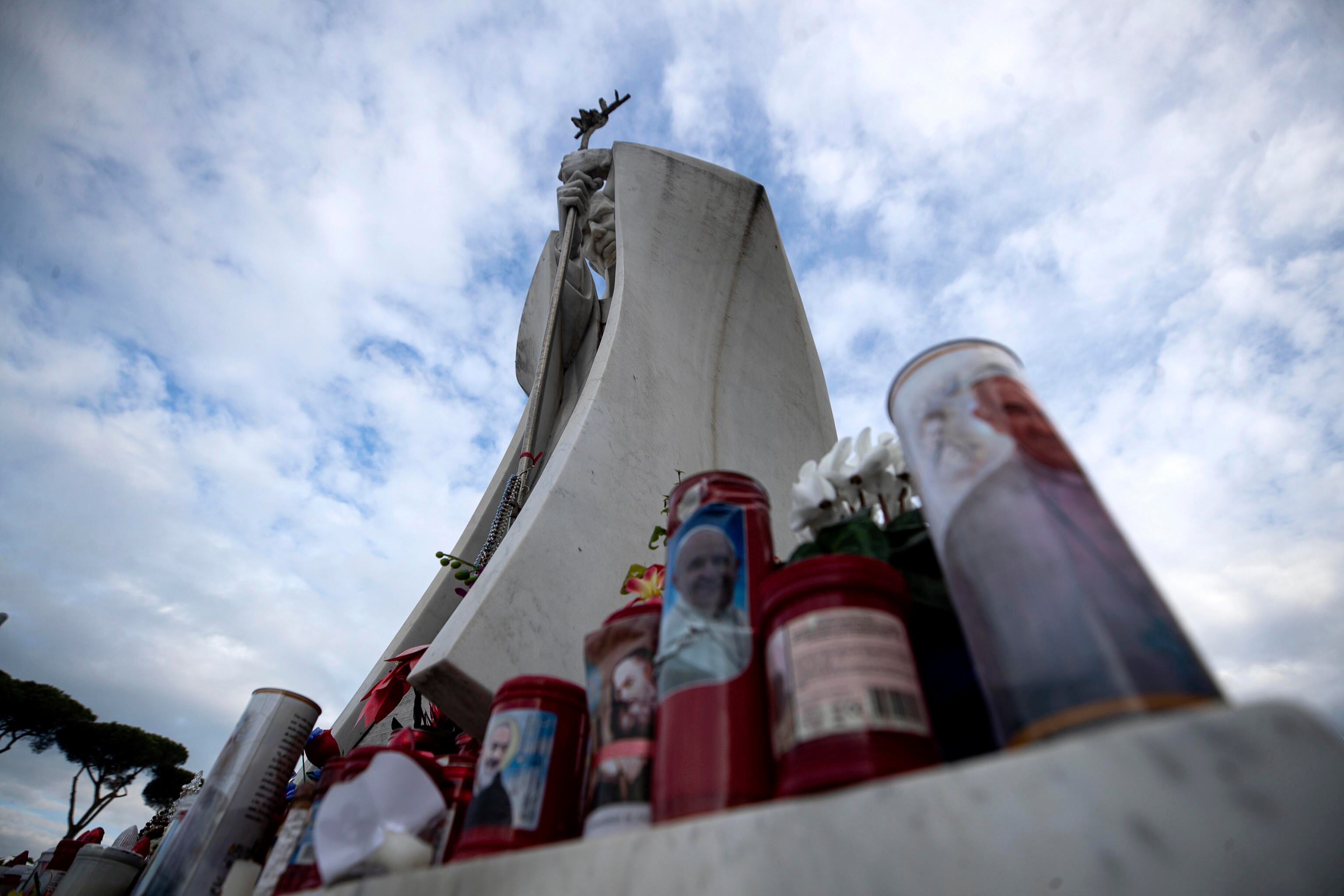 ROMA (Italia), 20/02/2025.- Flores y velas son depositadas a los pies de una estatua del Papa San Juan Pablo II fuera del Hospital Universitario Gemelli, donde el Papa Francisco está hospitalizado para pruebas y tratamiento de bronquitis.