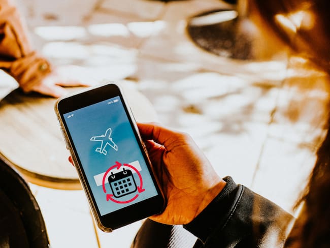 Mujer revisando su celular para reservar el vuelo (Getty Images)