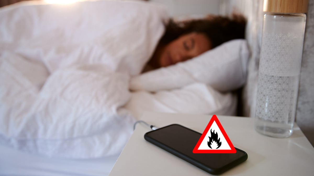 Celular cargando en la mesita de noche, mientras una mujer duerme al lado (Getty Images)
