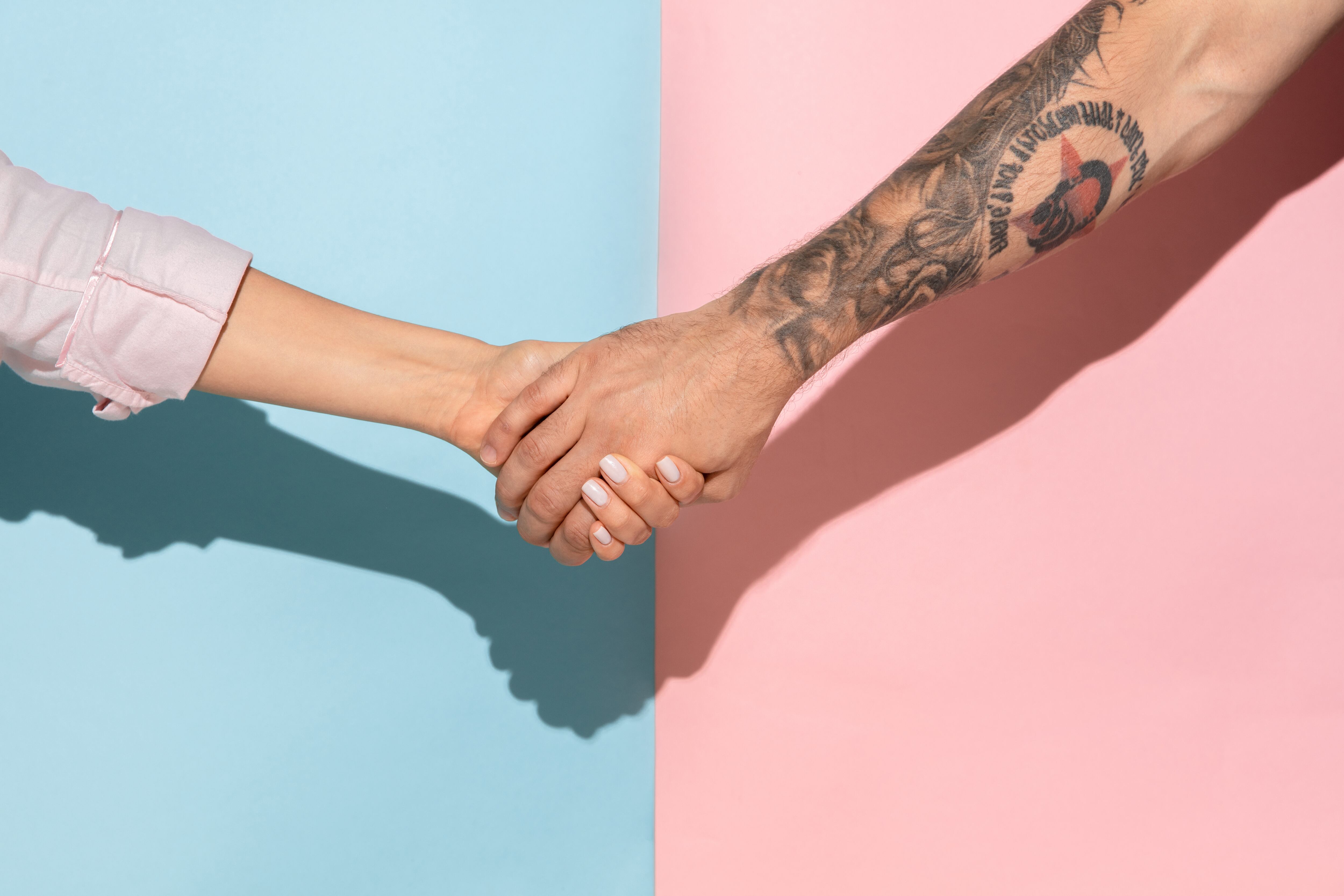Closeup shot of human holding hands isolated on blue-pink studio background. Concept of human relations, friendship, partnership, family. Copyspace.