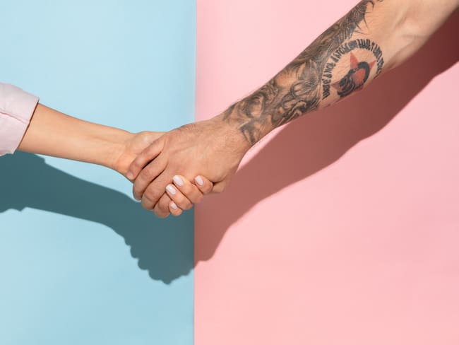 Closeup shot of human holding hands isolated on blue-pink studio background. Concept of human relations, friendship, partnership, family. Copyspace.