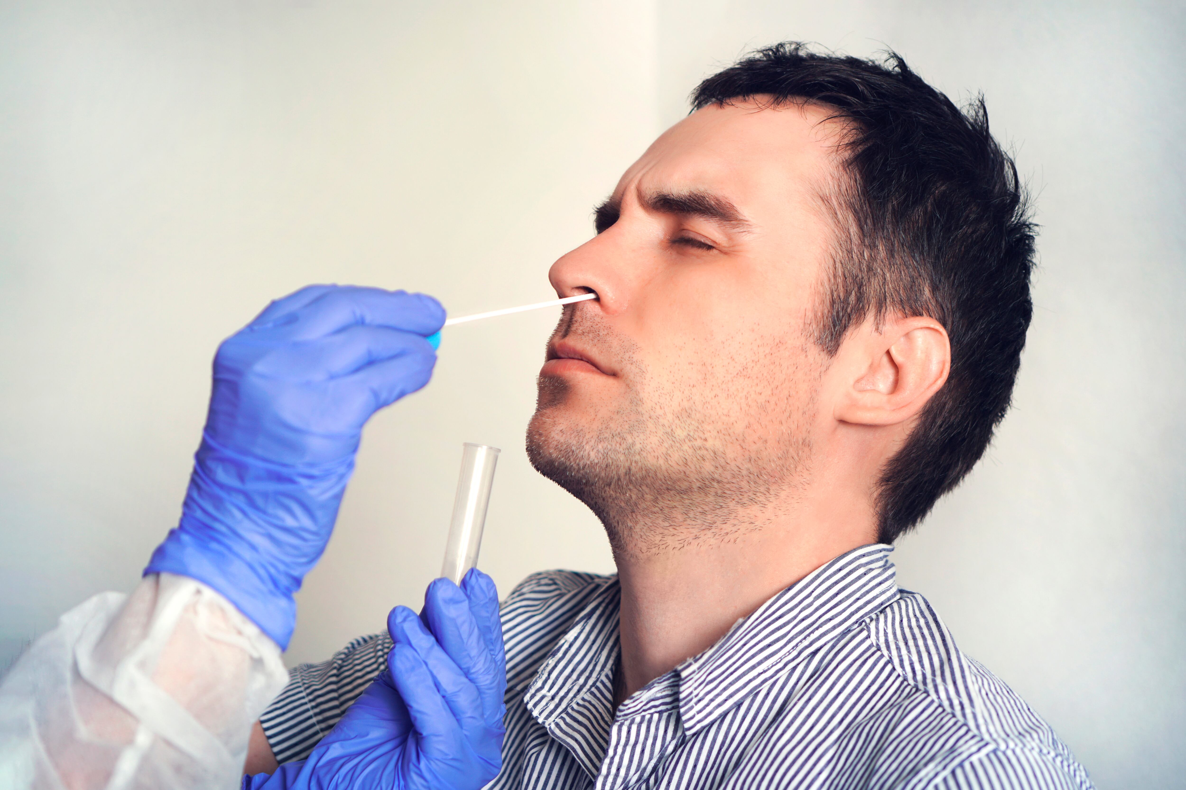 A doctor in a protective suit taking a nasal swab from a person to test for possible coronavirus infection. Nasal mucus testing for viral infections.