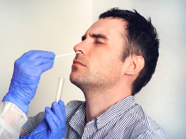 A doctor in a protective suit taking a nasal swab from a person to test for possible coronavirus infection. Nasal mucus testing for viral infections.