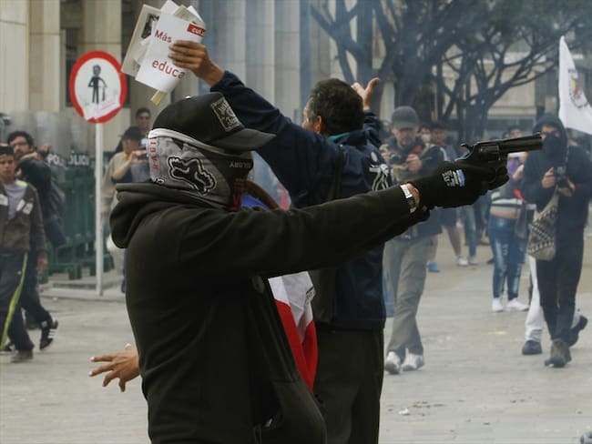 Un manifestante saca un arma en manifestación por el Día Internacional de los Trabajadores en Bogotá. Foto: EFE.