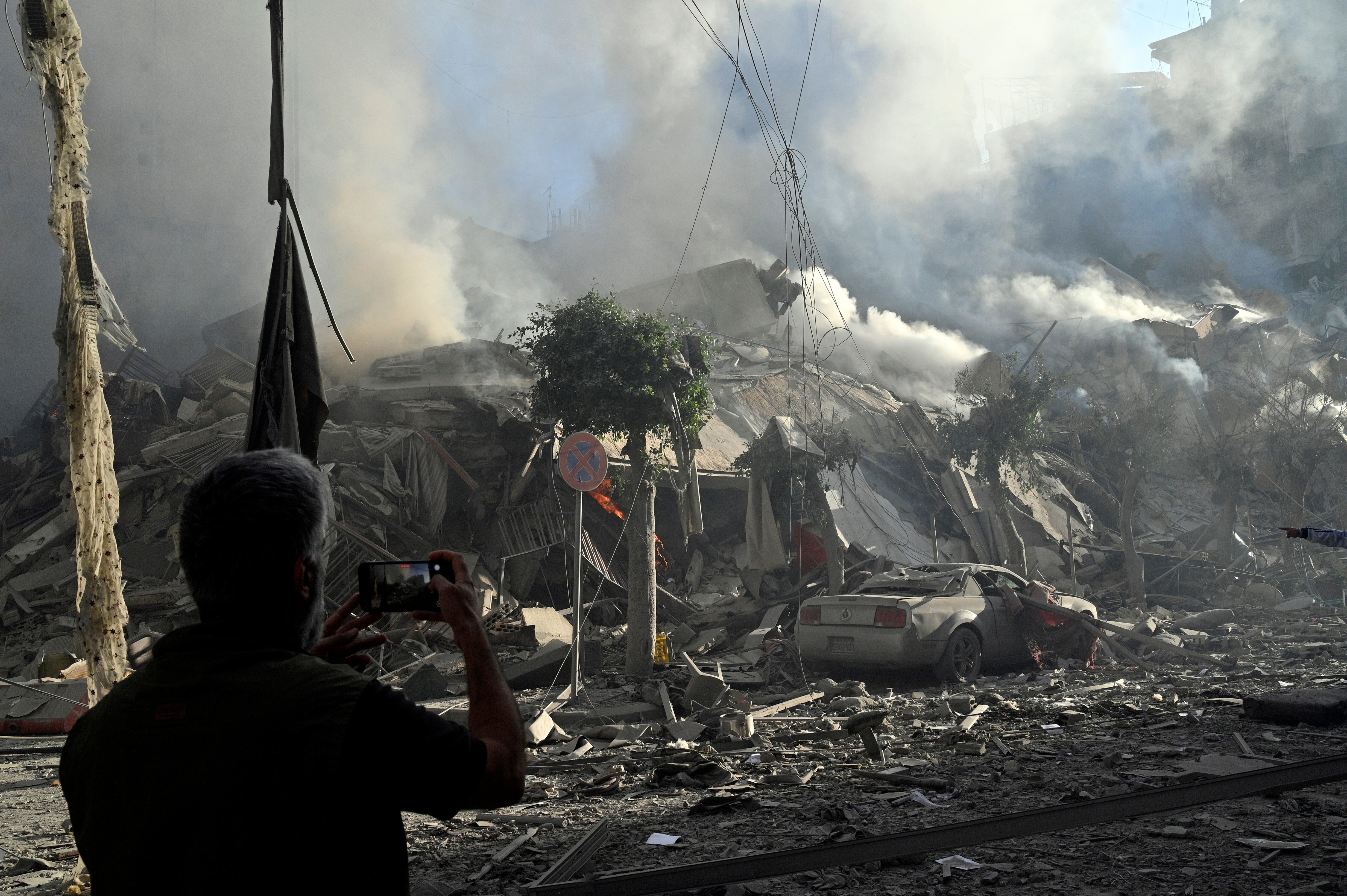 Beirut (Lebanon), 03/10/2024.- A man takes a photo as smoke rises from a damaged building following Israeli airstrikes in Dahieh, a southern suburb controlled by Hezbollah in Beirut, Lebanon, 03 October 2024. The Lebanese National News Agency (NNA) said that Israeli airstrikes were carried out overnight in the southern suburb, along with shelling from warships at sea. (Líbano, Hizbulá/Hezbolá) EFE/EPA/WAEL HAMZEH