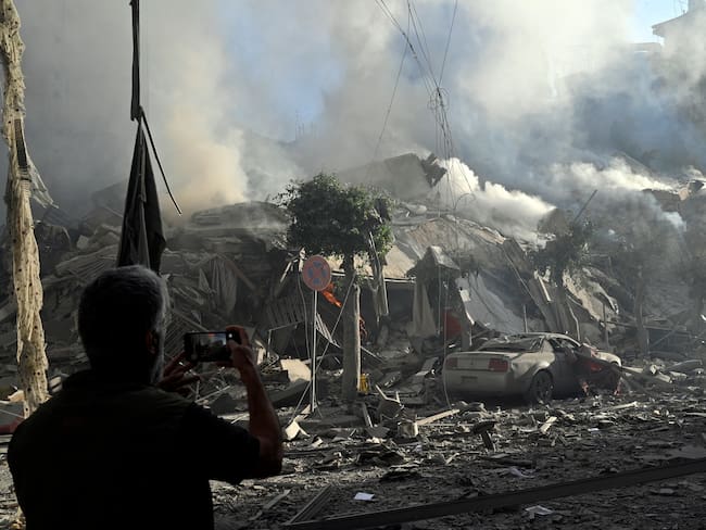 Beirut (Lebanon), 03/10/2024.- A man takes a photo as smoke rises from a damaged building following Israeli airstrikes in Dahieh, a southern suburb controlled by Hezbollah in Beirut, Lebanon, 03 October 2024. The Lebanese National News Agency (NNA) said that Israeli airstrikes were carried out overnight in the southern suburb, along with shelling from warships at sea. (Líbano, Hizbulá/Hezbolá) EFE/EPA/WAEL HAMZEH