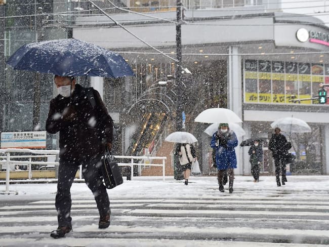 People cross the street as it snows in the city of Toyama, Toyama prefecture on the central-western coast of Japan, on January 24, 2023, as parts of the country brace for a severe winter storm. - Japan OUT (Photo by JIJI Press / AFP) / Japan OUT (Photo by STR/JIJI Press/AFP via Getty Images)