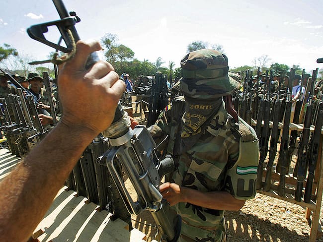 LA MESA, COLOMBIA: A member of the Colombian United Self -Defense (AUC) right-wing paramilitary guerrillas hands over his weapon during the demobilization ceremony 10 March, 2006 in La Mesa , department of Cesar, Colombia. Paramilitaries fighters demobilized friday in Colombia one the last surrendered arms, according to the schedule agreed with the government of President Alvaro Uribe. AFP PHOTO/Rodrigo ARANGUA (Photo credit should read RODRIGO ARANGUA/AFP via Getty Images)
