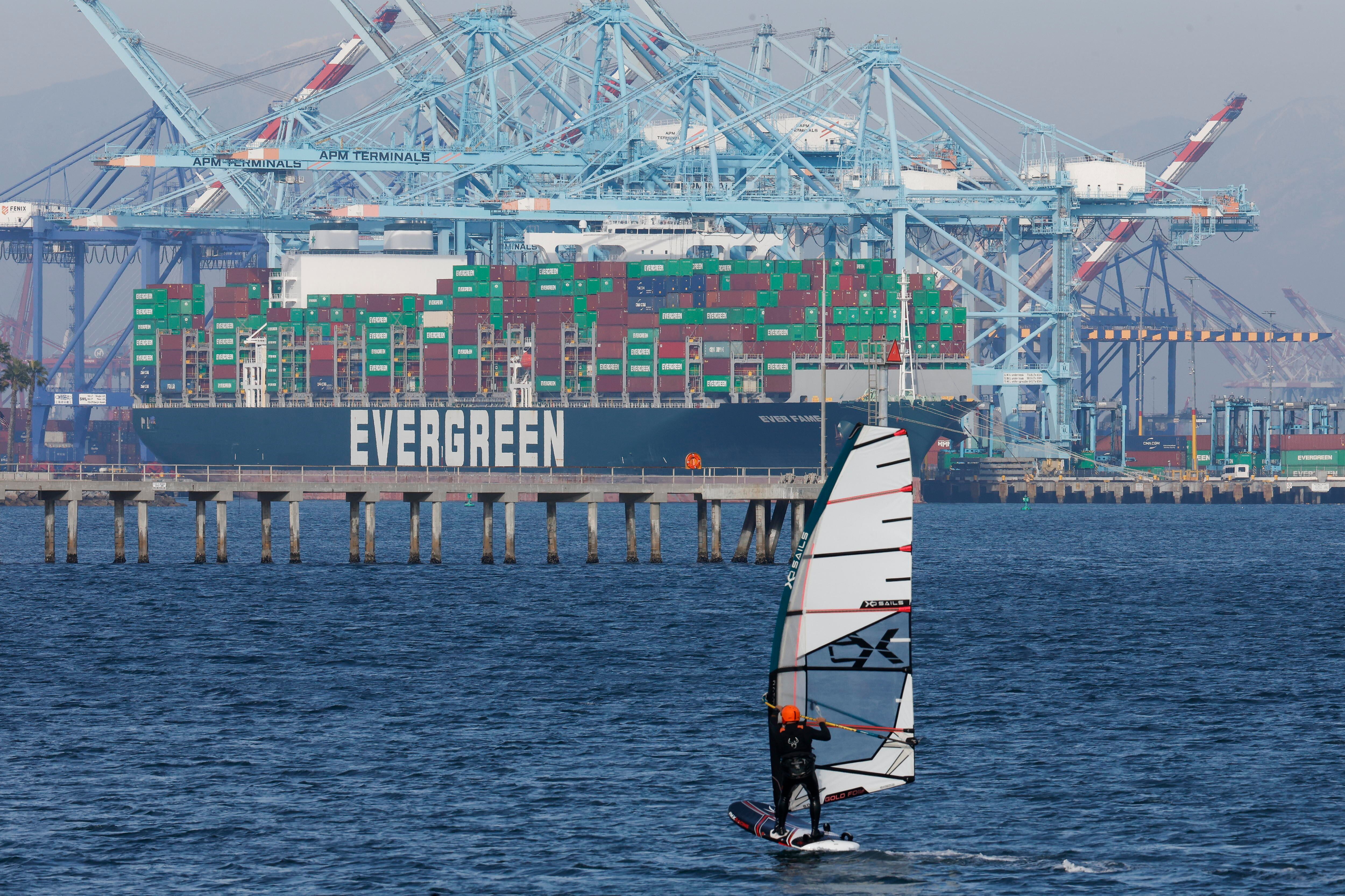 Long Beach (Usa), 04/02/2025.- Una persona navega cerca de un barco con contenedores de carga Evergreen en el Puerto de Los Ángeles.