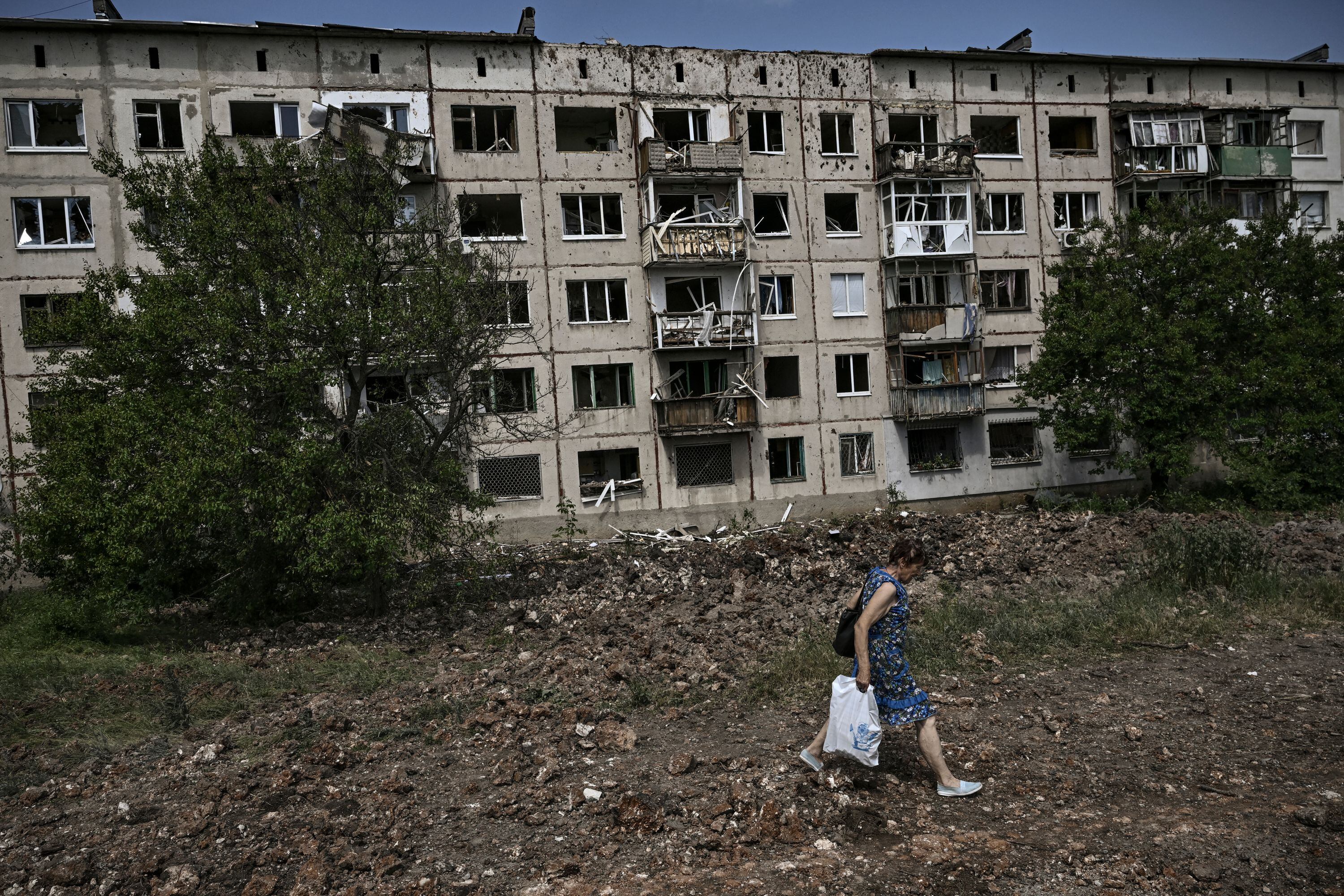 A woman walks in front of damaged apartment building after a missile strike in the city of Soledar, in the eastern Ukrainian region of Donbas on June 4, 2022. (Photo by ARIS MESSINIS / AFP) (Photo by ARIS MESSINIS/AFP via Getty Images)