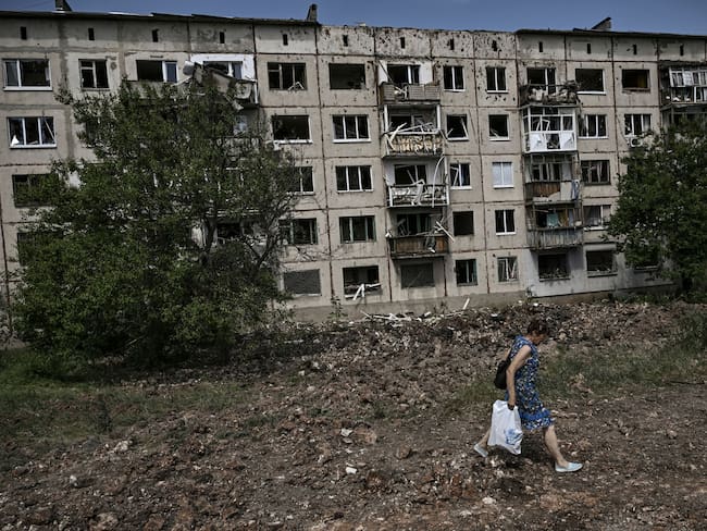 A woman walks in front of damaged apartment building after a missile strike in the city of Soledar, in the eastern Ukrainian region of Donbas on June 4, 2022.  (Photo by ARIS MESSINIS / AFP) (Photo by ARIS MESSINIS/AFP via Getty Images)