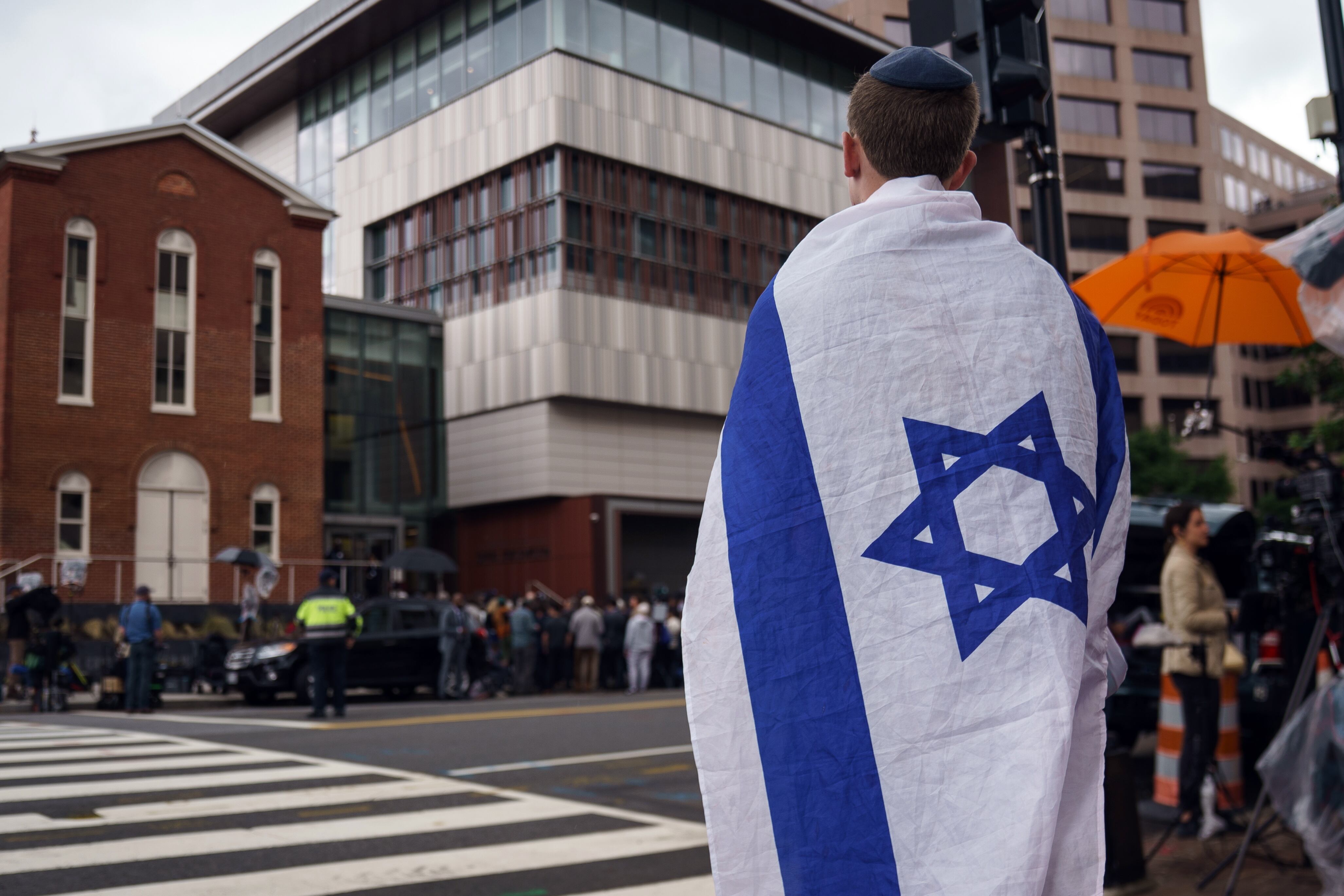 WASHINGTON (United States), 22/05/2025.- A member of the public with the Israeli flag draped over the shoulders stands close to the scene where two people were shot and killed at the Capital Jewish Museum in Washington, DC, USA, 22 May 2025. According to a social media post by the US Homeland Security Secretary Kristi L. Noem, the two people killed last night were staff members at the Israeli embassy. EFE/EPA/WILL OLIVER