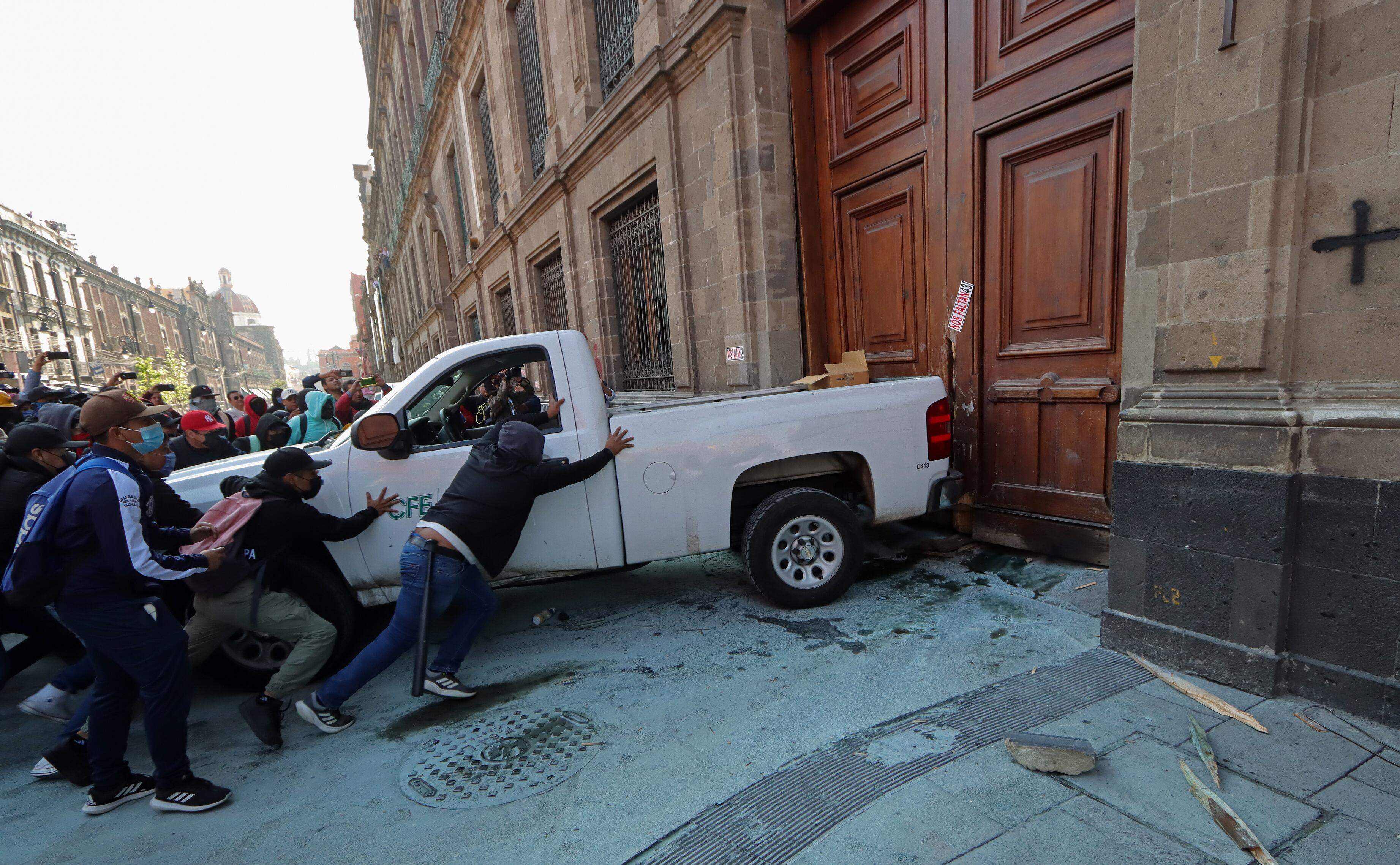 MEX952. CIUDAD DE MÉXICO (MÉXICO), 06/03/2024.- Manifestantes encapuchados usan un vehículo para vandalizar una de las puertas del Palacio Nacional este miércoles, en Ciudad de México (México). Jóvenes mexicanos que protestan por la desaparición de los 43 estudiantes de Ayotzinapa rompieron este miércoles una de las puertas principales del Palacio Nacional mientras el presidente, Andrés Manuel López Obrador, realizaba adentro su conferencia matutina. Los manifestantes, quienes acusan a López Obrador de no resolver el caso para proteger a militares involucrados, tomaron una camioneta que pertenece a la Comisión Federal de Electricidad (CFE) para tumbar la puerta 1 sobre la calle Moneda del centro histórico de Ciudad de México. EFE/ Madla Hartz