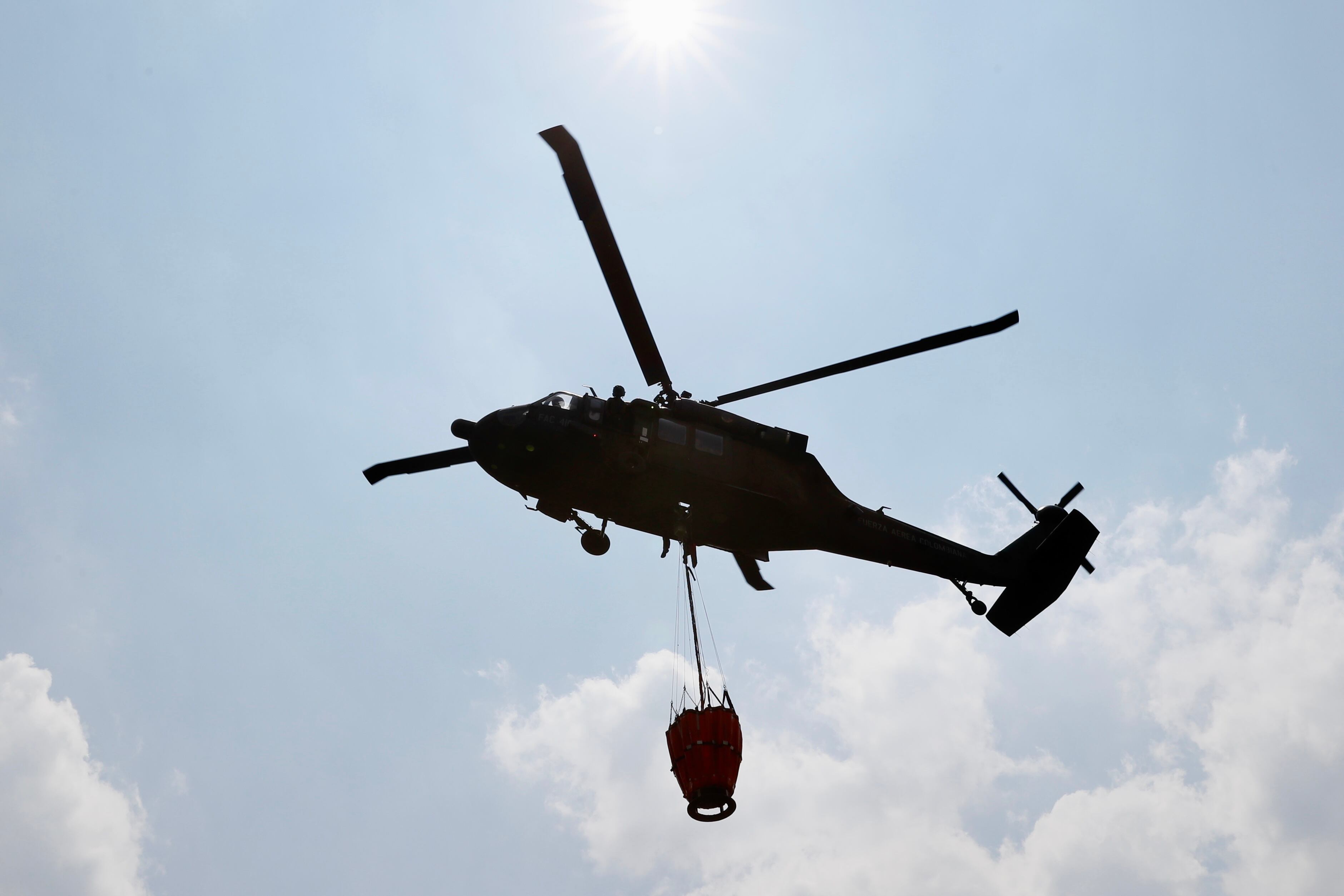 Un helicóptero de la Fuerza Aeroespacial Colombiana (FAC) reabastece con agua el sistema Bambi Bucket para combatir los incendios de los cerros orientales, en Bogotá (Colombia). El número de incendios activos en Colombia descendió a 13 este domingo, cuatro menos de los que había el sábado, y las autoridades continúan trabajando para apagar los fuegos que han afectado bosques, páramos y vegetación, principalmente, de la región andina. EFE/ Carlos Ortega
