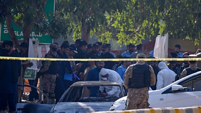 Policemen examine a car after a suicide blast in Islamabad on November 11, 2025. A suicide bombing outside district court buildings in a residential area of the Pakistani capital killed 12 people and wounded 27 on November 11, the interior minister said. (Photo by Farooq NAEEM / AFP)