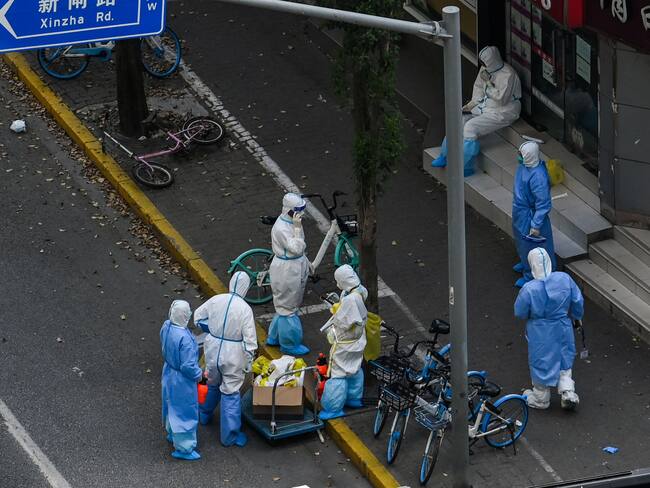 Health workers wearing personal protective equipment (PPE) stand next to the entrance of a neighborhood during a COVID-19 lockdown in the Jing&#039;an district in Shanghai on April 12, 2022. (Photo by HECTOR RETAMAL / AFP) (Photo by HECTOR RETAMAL/AFP via Getty Images)