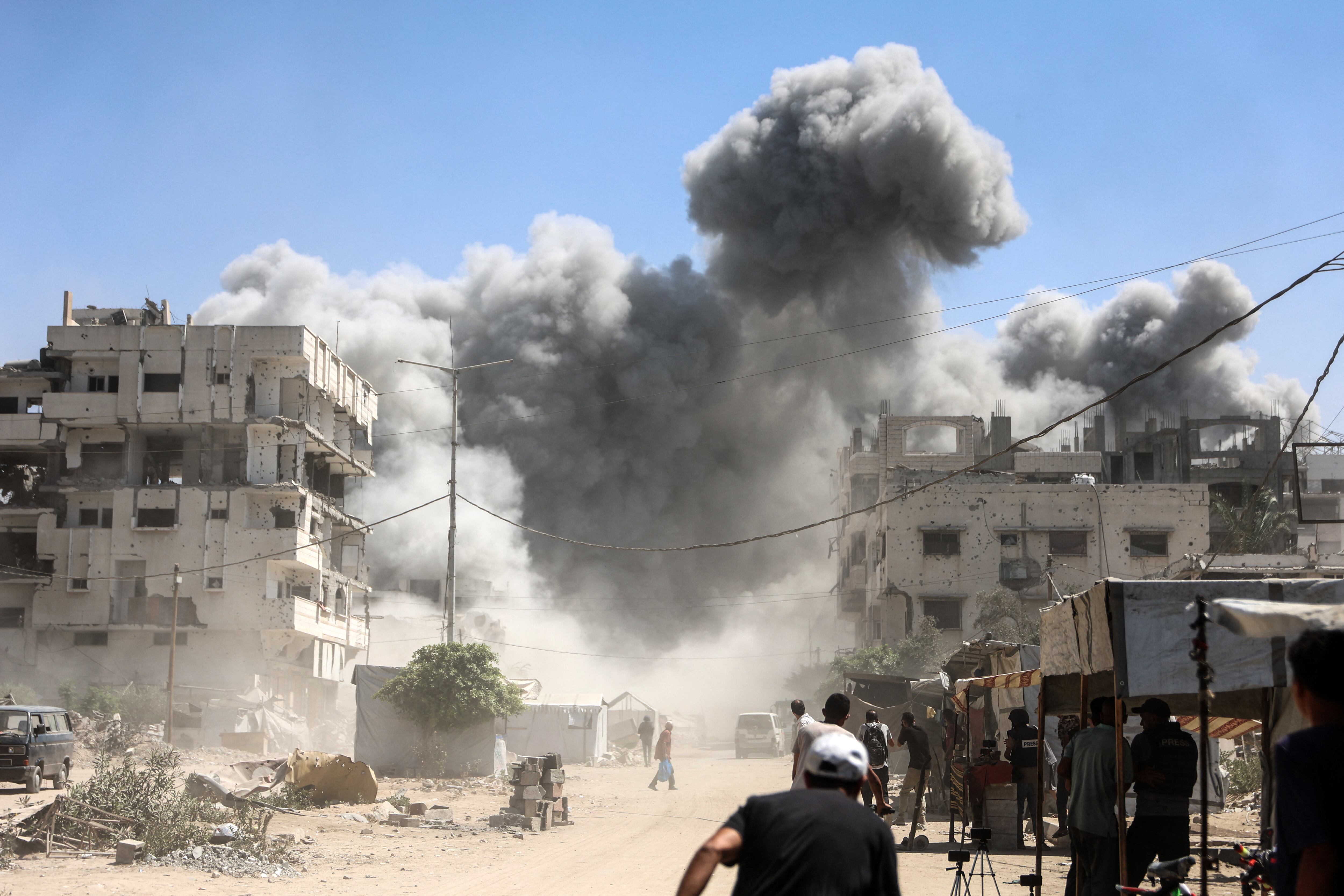 Palestinians watch as the Mhanna tower collapses amid heavy smoke, during an Israeli strike in the Tal el-Hawa neighbourhood of Gaza City on September 14, 2025. The Israeli military has issued multiple evacuation warnings for Gaza City, but many residents have told AFP they have nowhere else to go, noting that Israel has repeatedly struck the area in the south where it has urged people to move. (Photo by Omar AL-QATTAA / AFP)