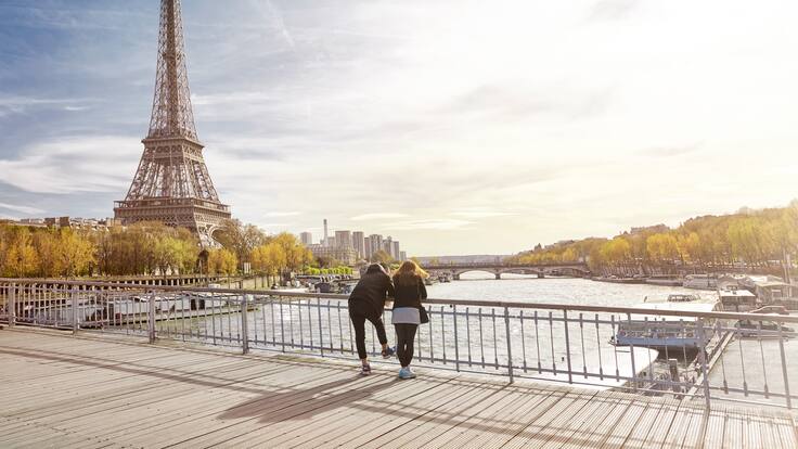 Pareja de turistas mirando la torre Eiffel en París, Francia (Foto vía GettyImages)