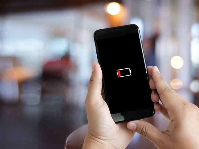 Hombre revisando su celular que se apagó por baja batería (Getty Images)