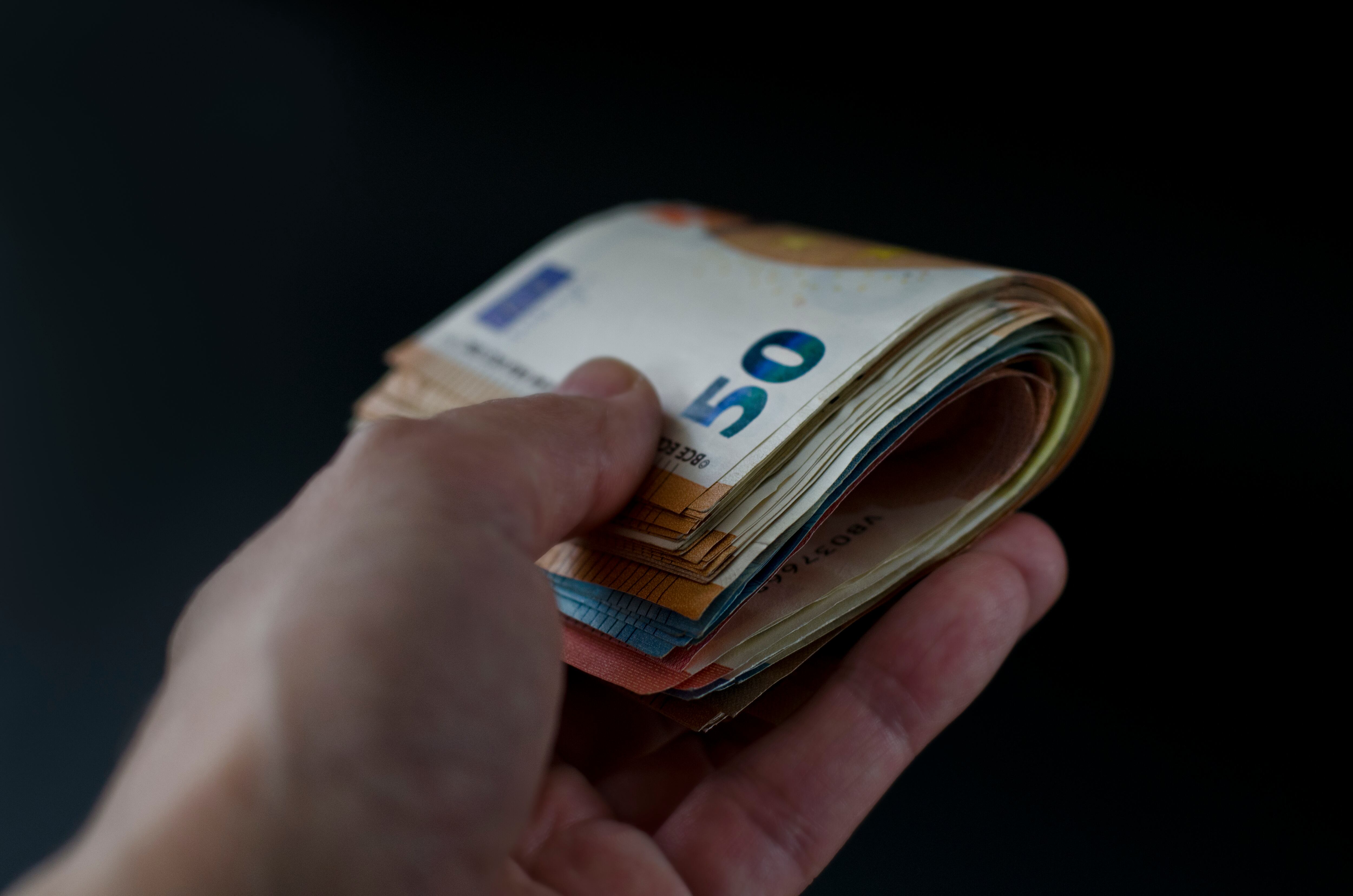 Euro banknotes in hand close-up on black background