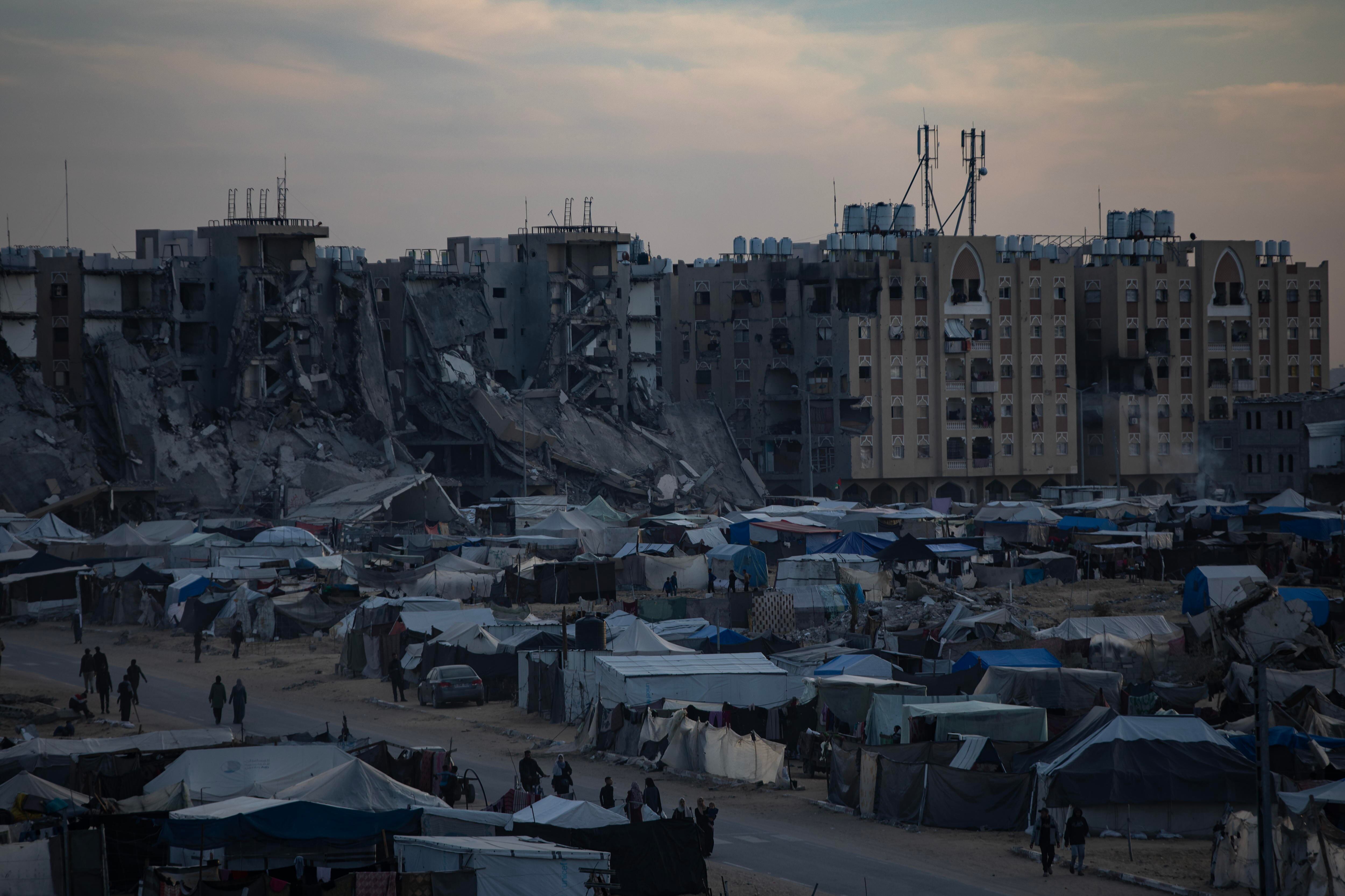 Khan Yunis (-), 22/12/2024.- Palestinos desplazados, que huyeron de sus hogares debido a los ataques aéreos israelíes y a las órdenes de evacuación, caminan entre tiendas de campaña en un campamento improvisado al atardecer en el campo de Khan Younis, sur de la Franja de Gaza, EFE/EPA/HAITHAM IMAD