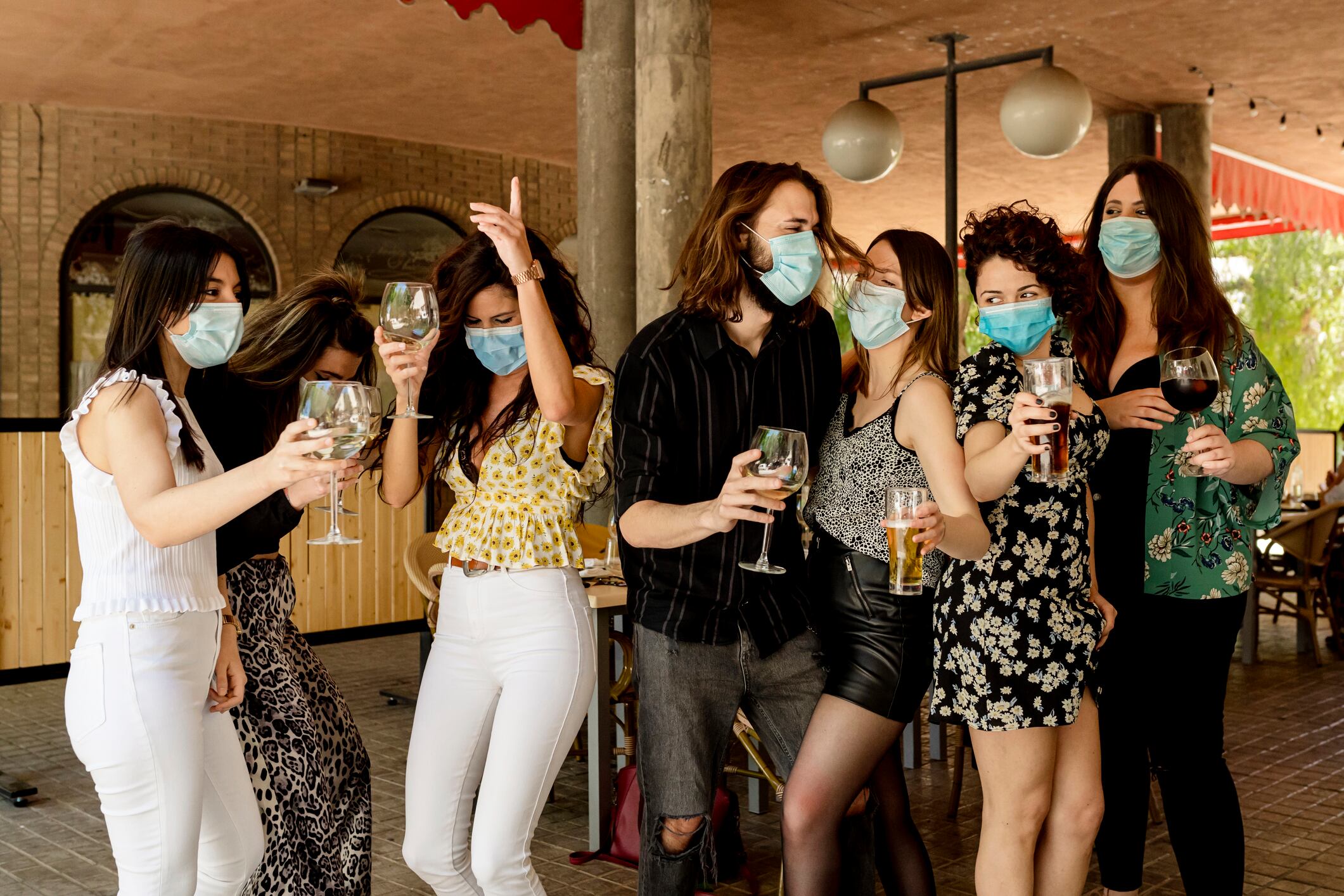 Valencia, Spain, friends with masks on the terrace of the restaurant toasting during the day