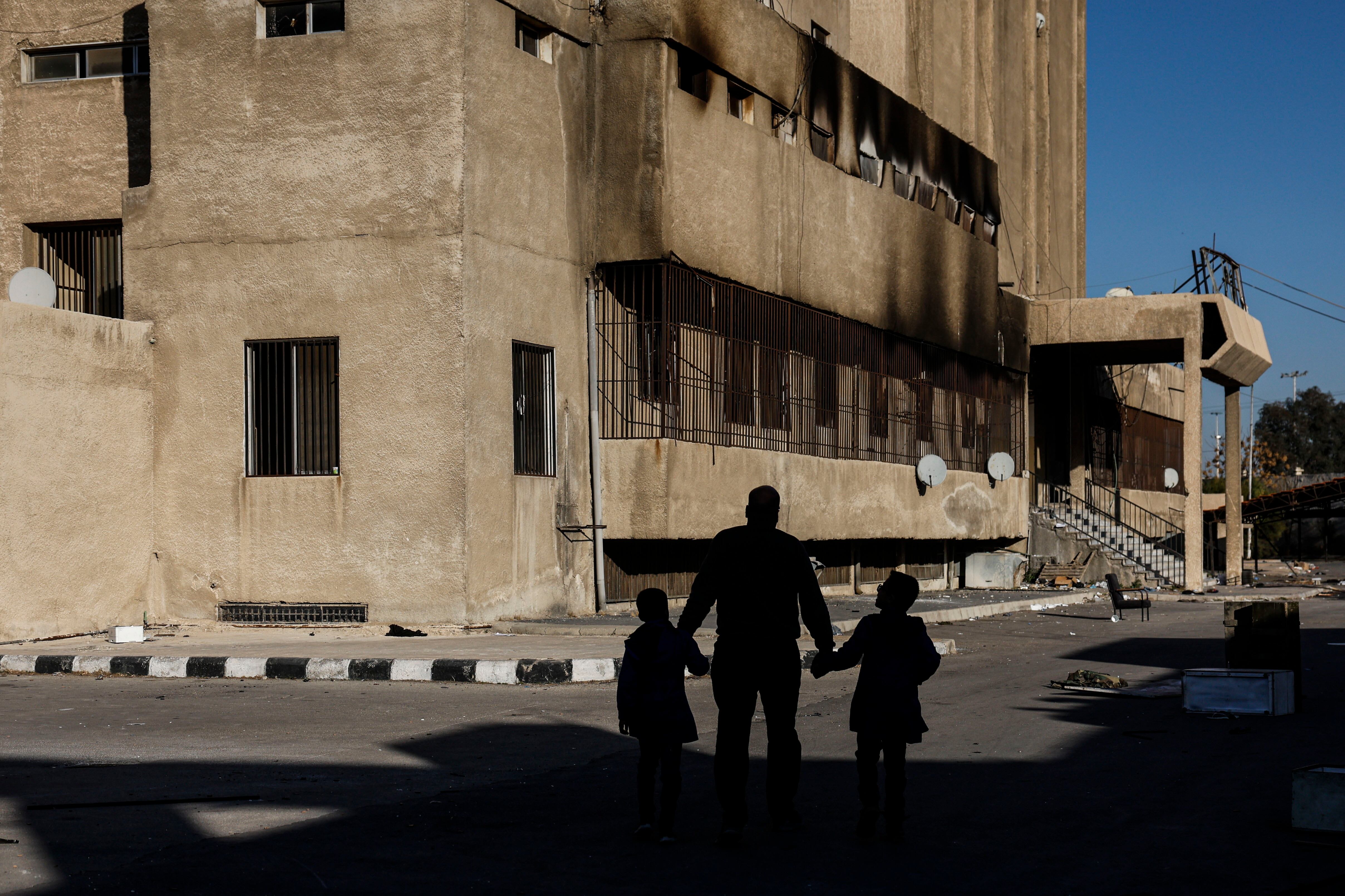 Damascus (Syrian Arab Republic), 18/12/2024.- A man walks with two children outside the Palestine's Station Prison, headquarters of the Syrian secret services. EFE/EPA/ANTONIO PEDRO SANTOS
