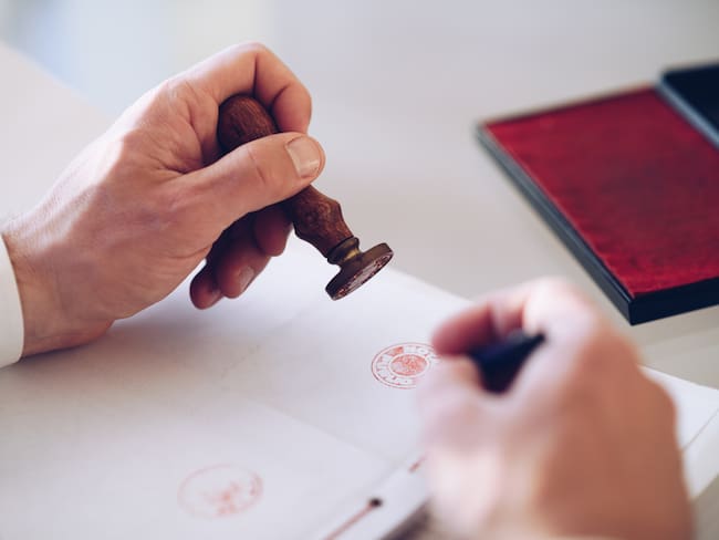Trabajador de una notaría poniendo un sello a un documento / Foto: GettyImages