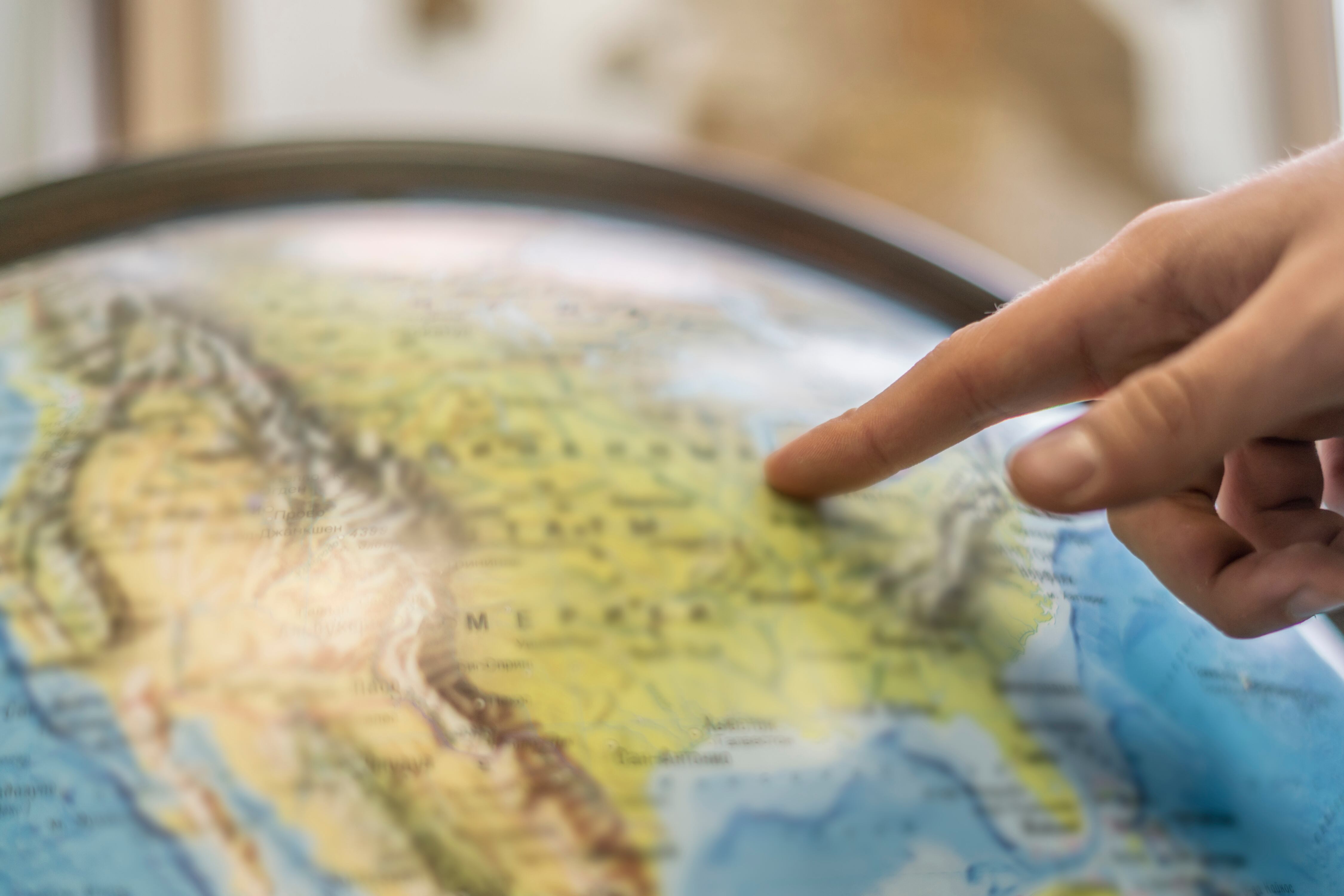 Persona señalando un país en un globo terráqueo (GettyImages)