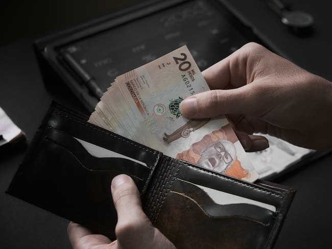 Hombre sacando billetes de 20.000 pesos de su billetera. Foto: Getty Images.